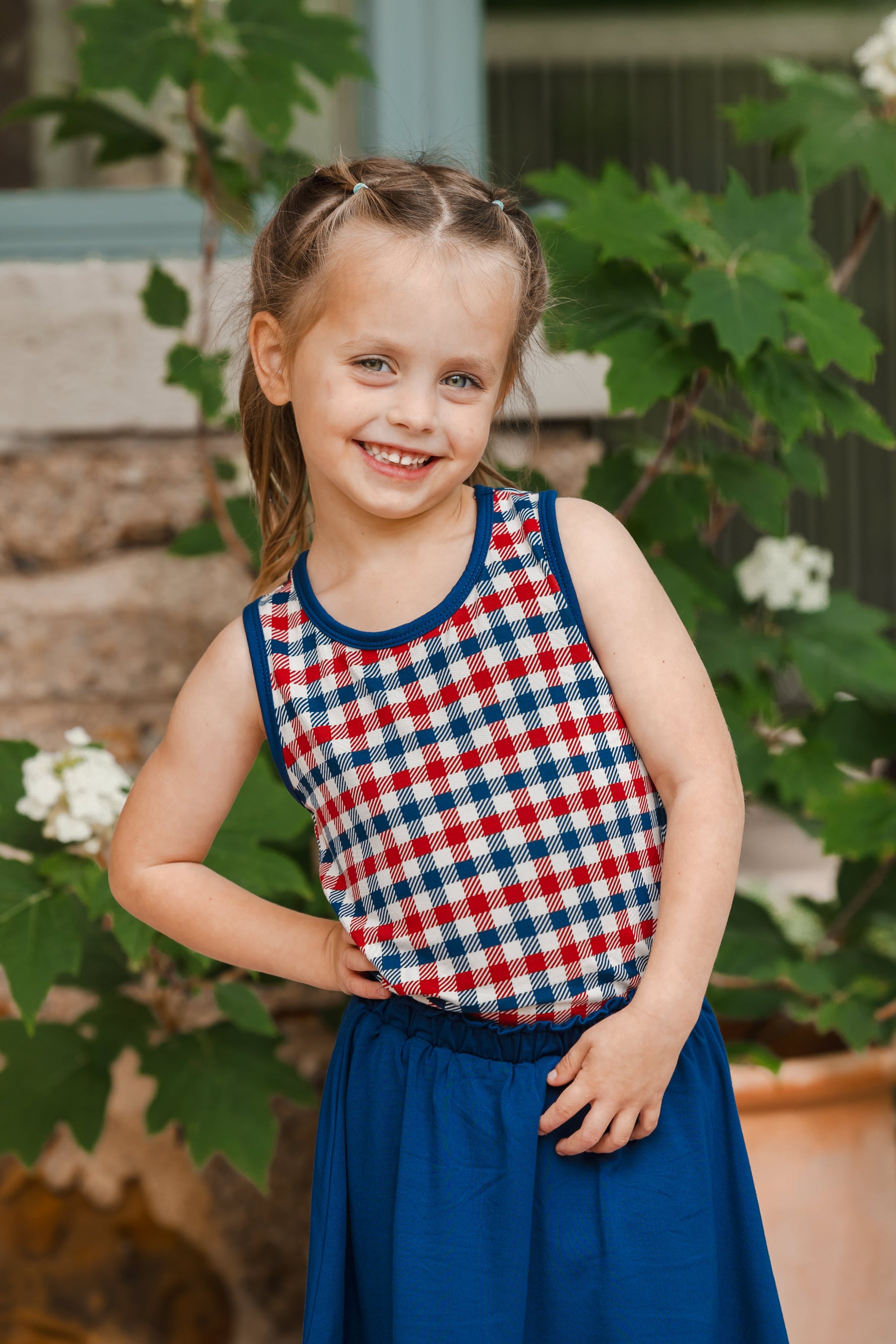 Child smiling in red blue and white Patriotic Gingham check print toddler tank top over a Tahoe skort