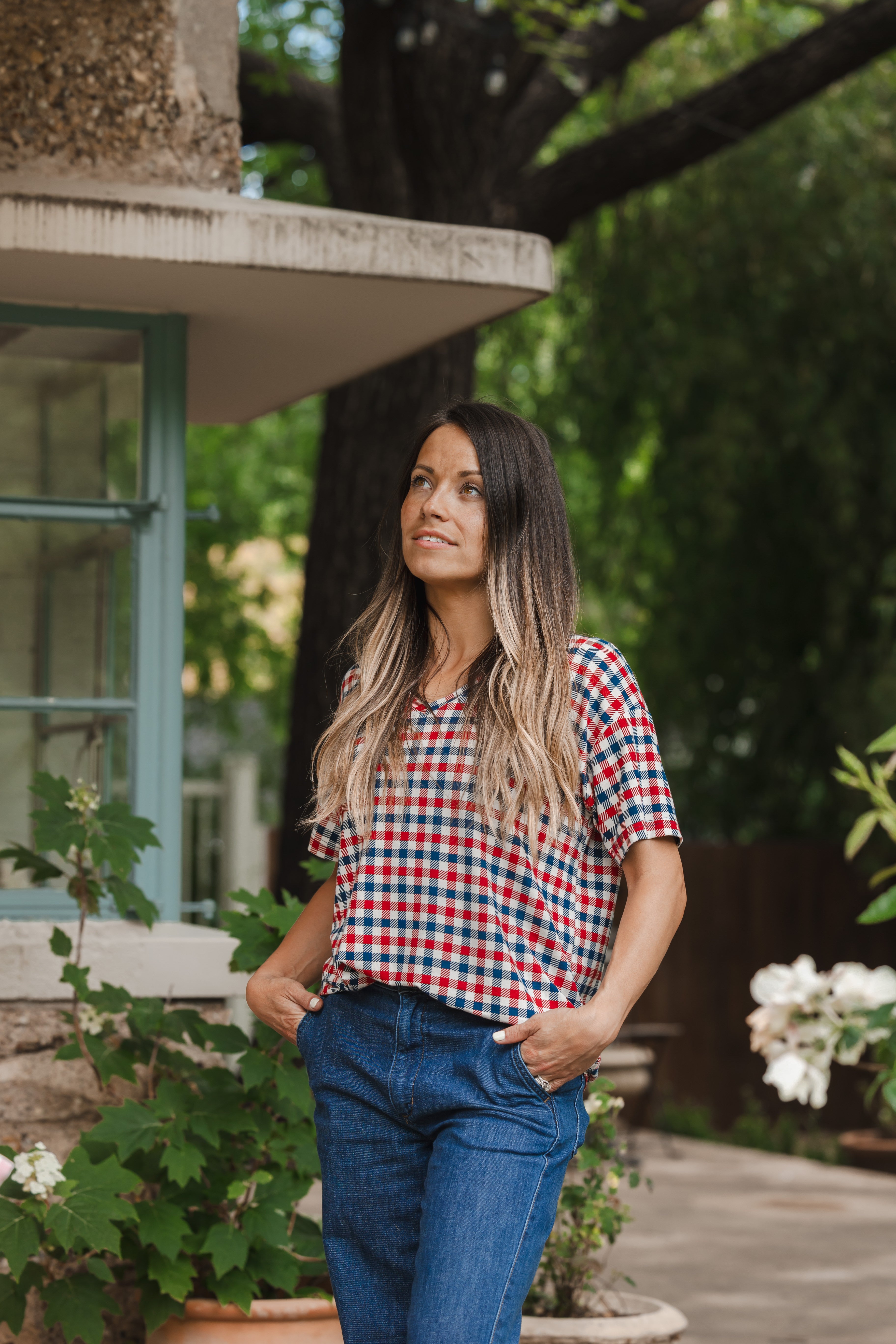 Model wearing Women's Relaxed Fit V-Neck in red blue and white Patriotic Gingham check print over denim pants