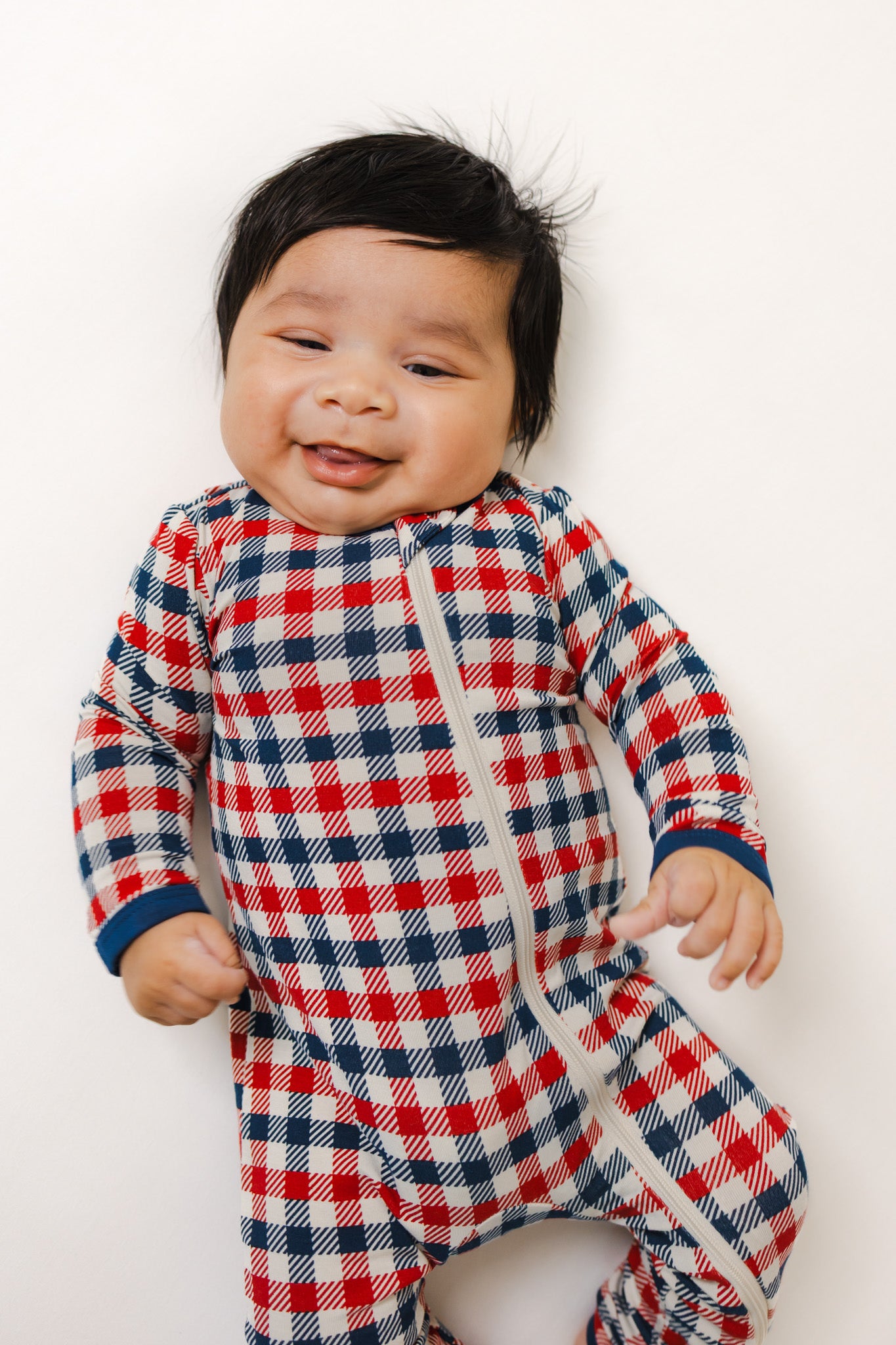 Baby wearing red blue and white Patriotic Gingham check print zippered romper on a white background
