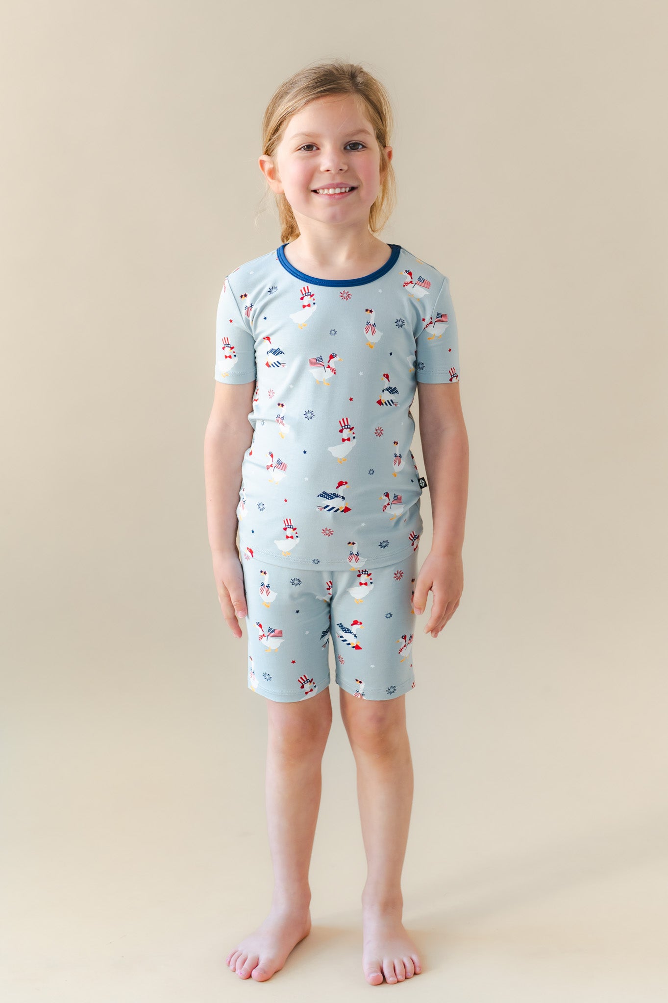 Child wearing light blue Short Sleeve Pajamas in Patriotic Goose print on a beige background