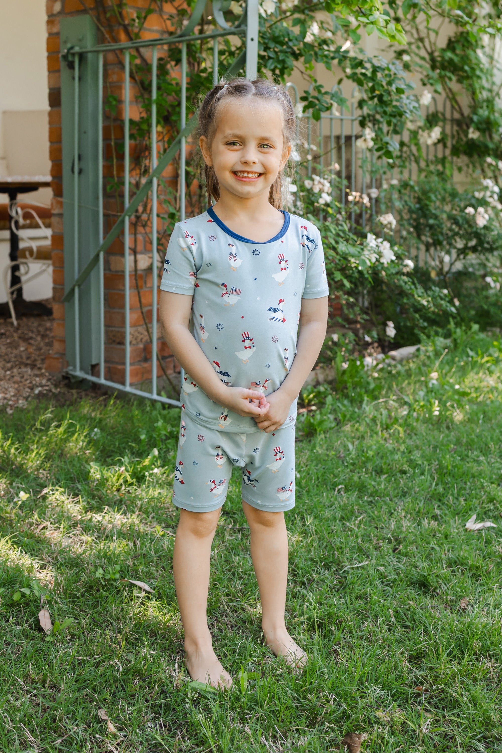 Child wearing Light blue Short Sleeve Pajamas with Patriotic Goose print standing outdoors on a grass