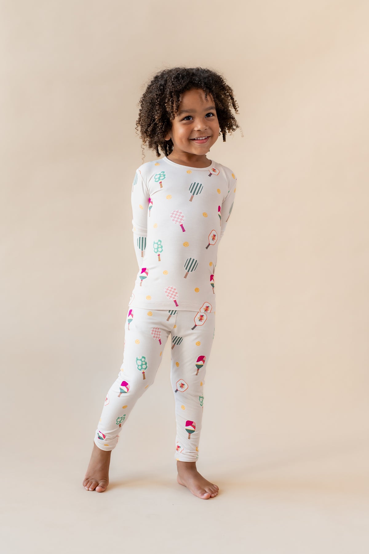 Girl wearing Long Sleeve Pajamas in Pickleball print on a beige background