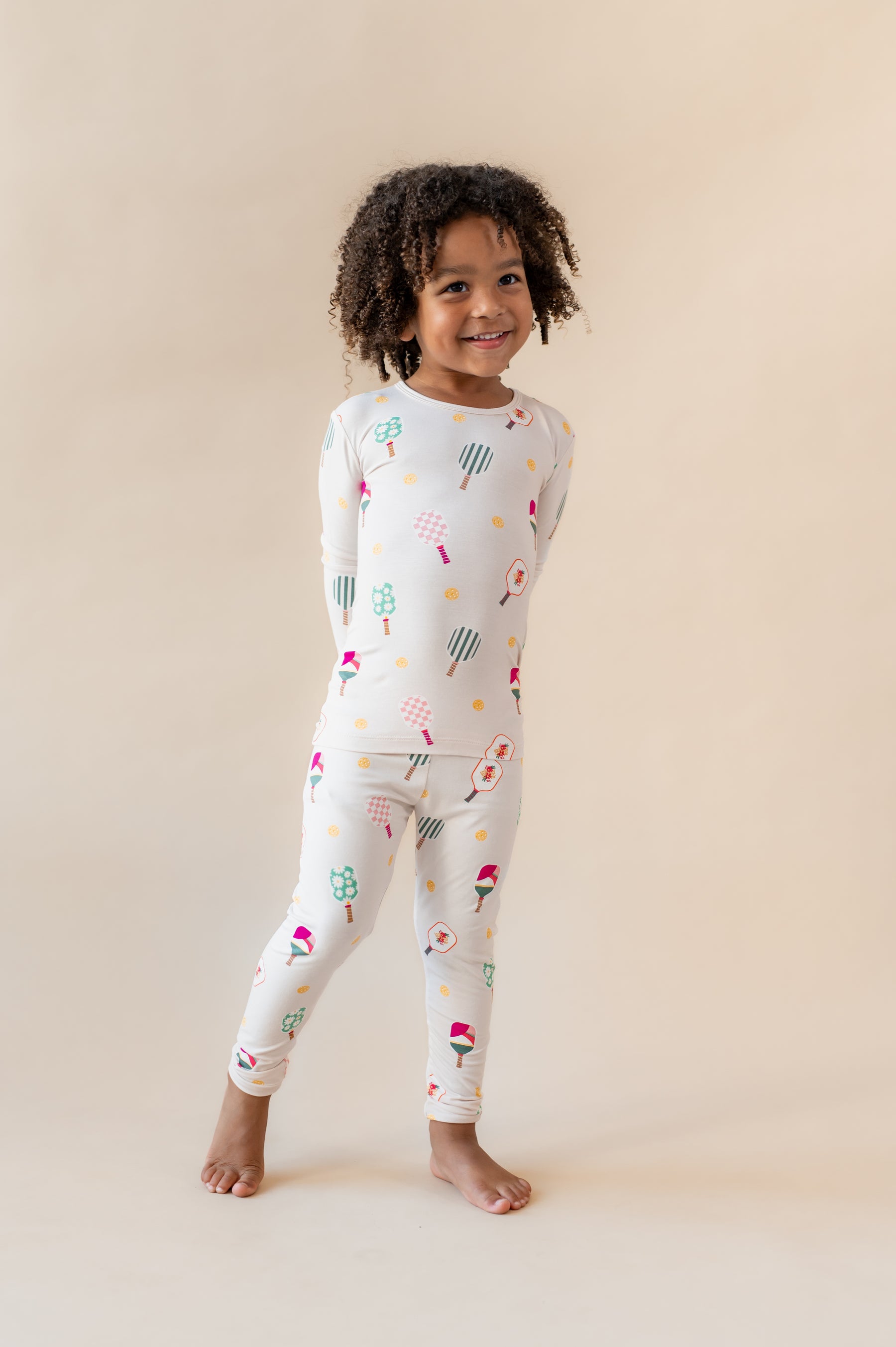 Girl wearing Long Sleeve Pajamas in Pickleball print on a beige background
