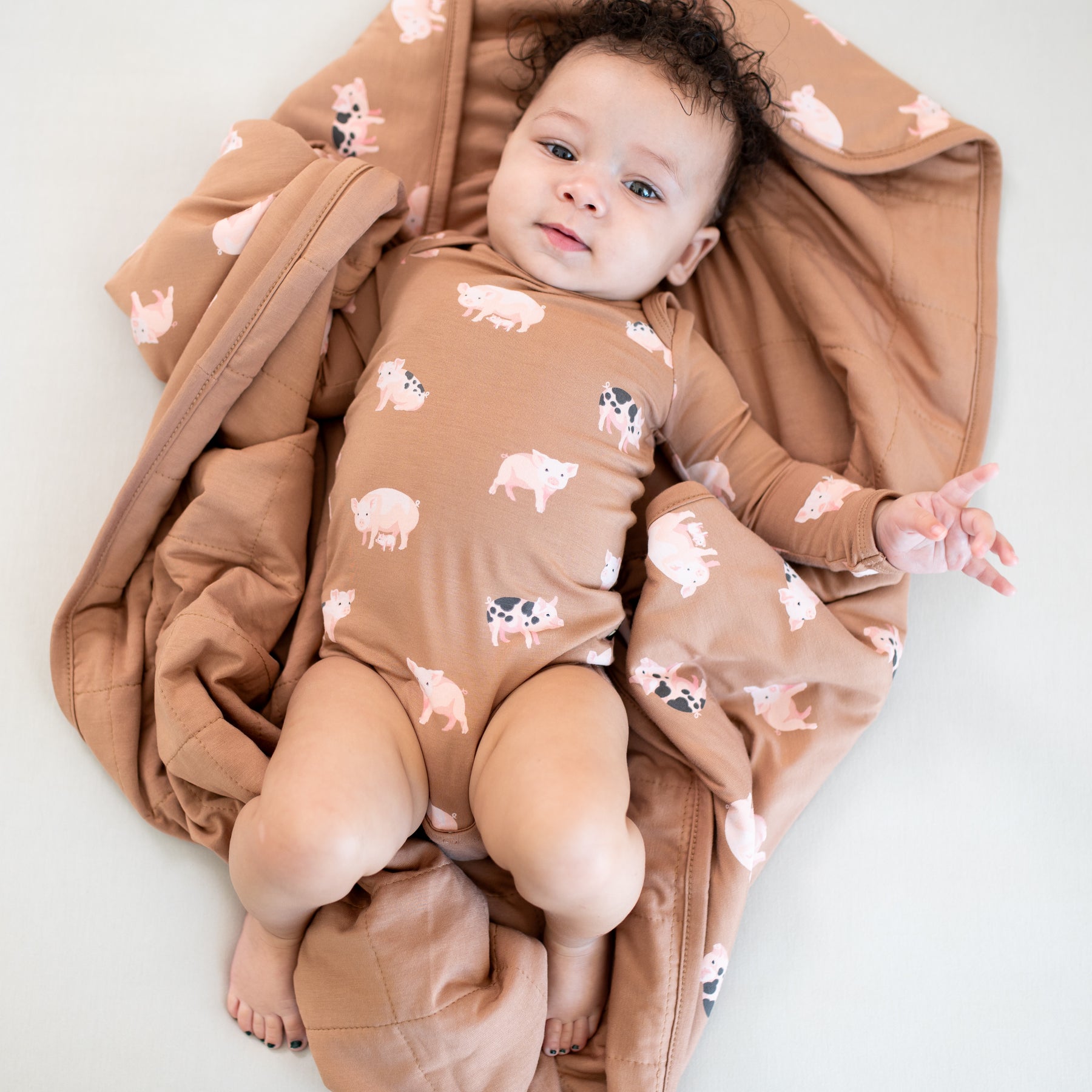 Infant wearing long sleeve farm animal onesie and laying on Baby Blanket in Pig 1.0 TOG