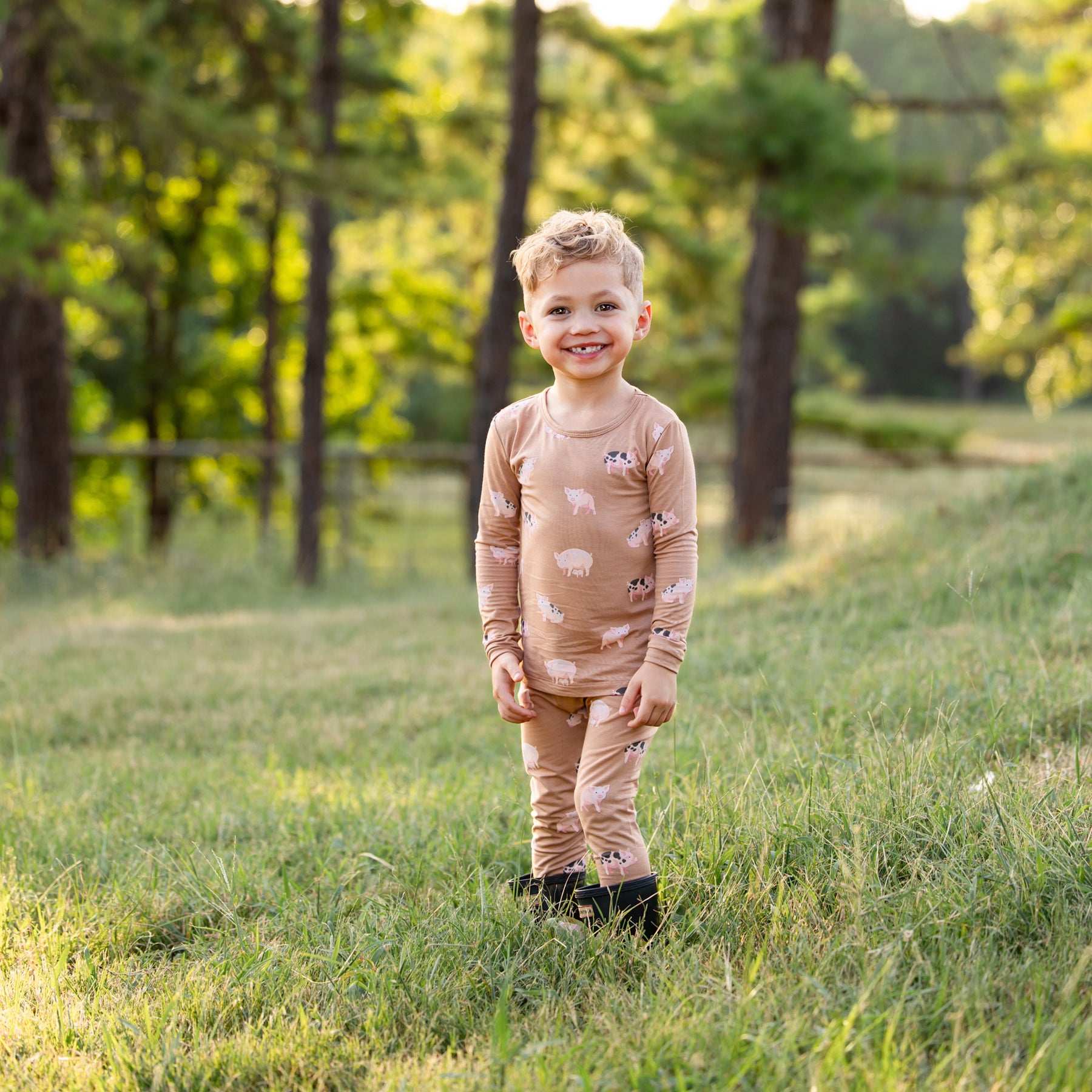 Boy standing in a field wearing the Long Sleeve Pajamas in Pig 