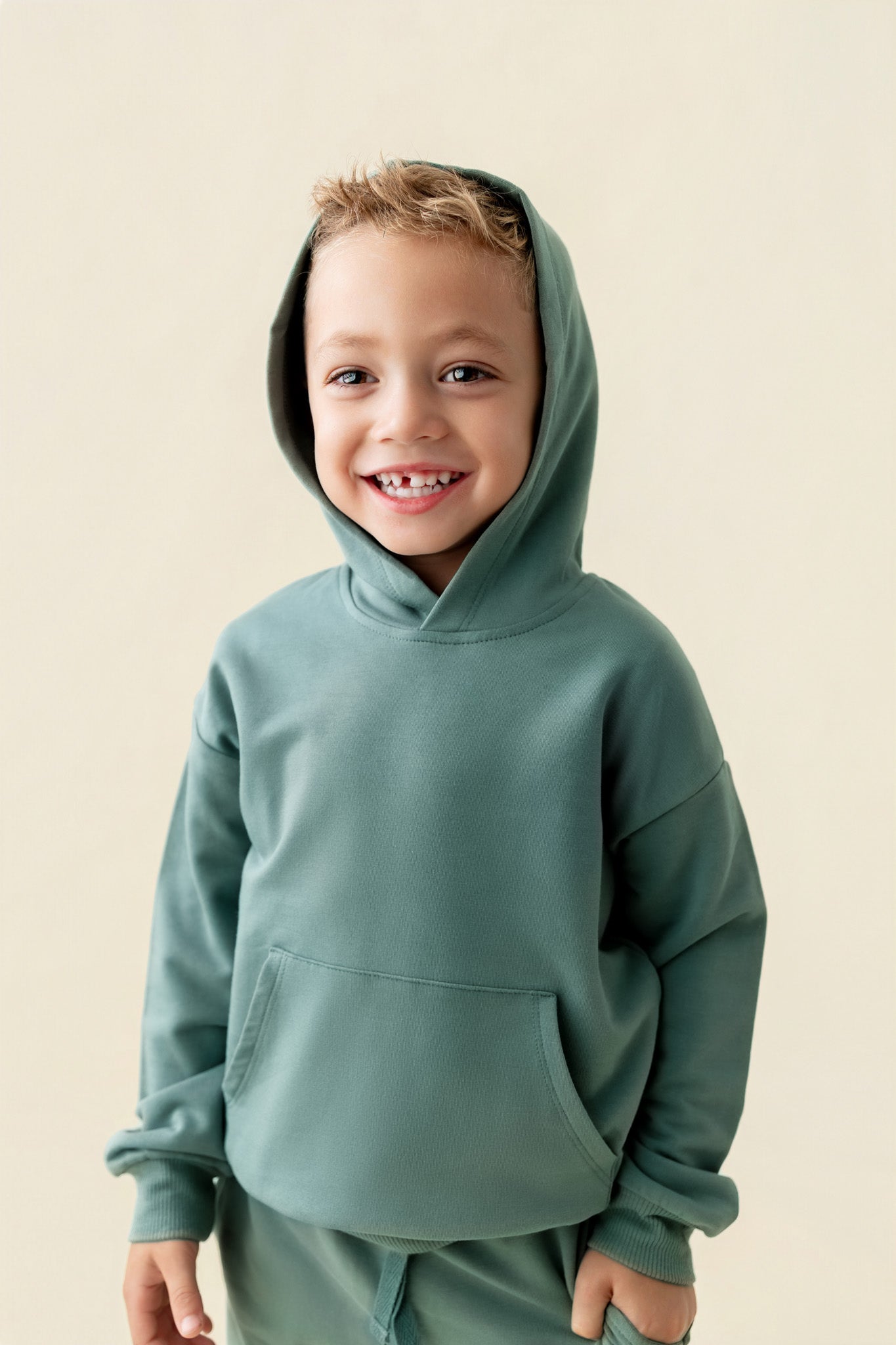 Boy wearing Hoodie in Pine color on a beige background