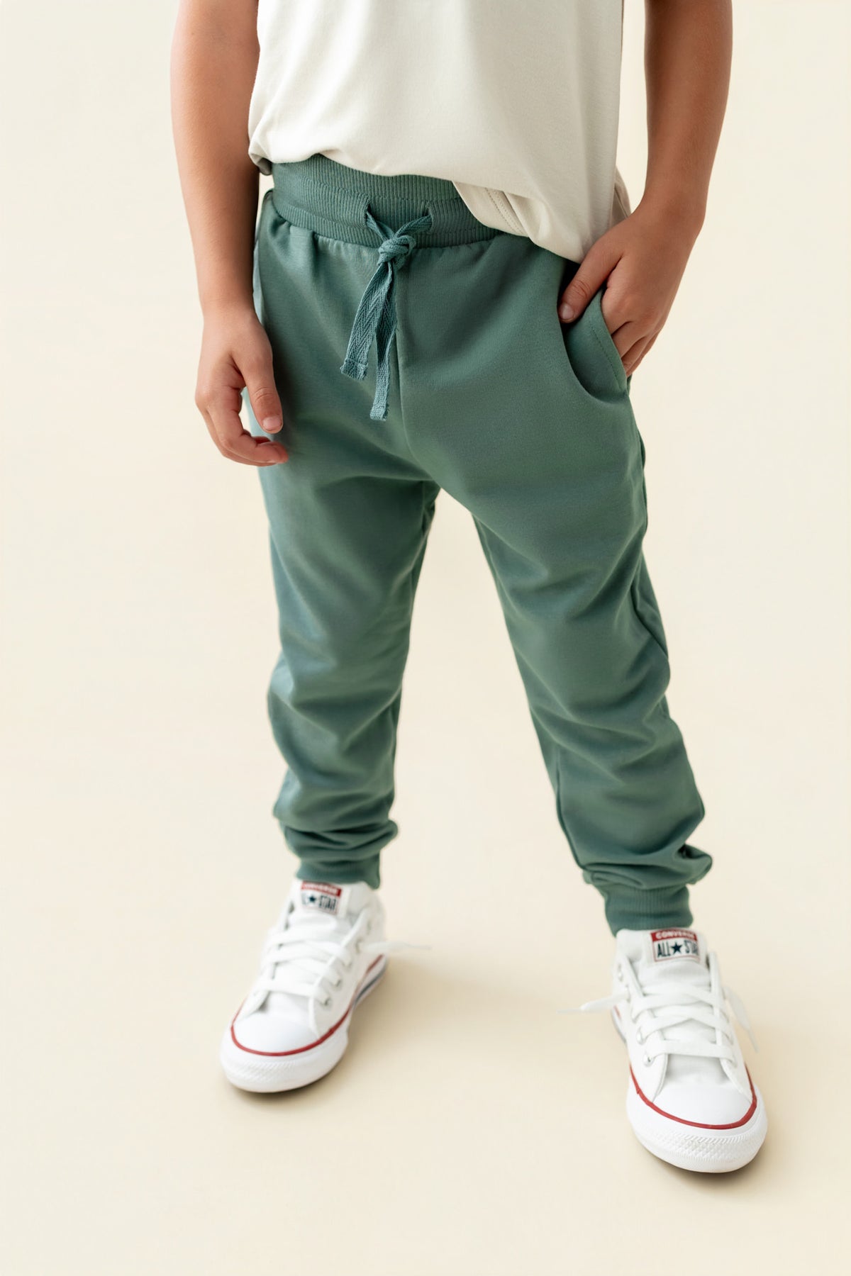 Modal wearing Jogger Pant in Pine color under white T-shirt on a beige background