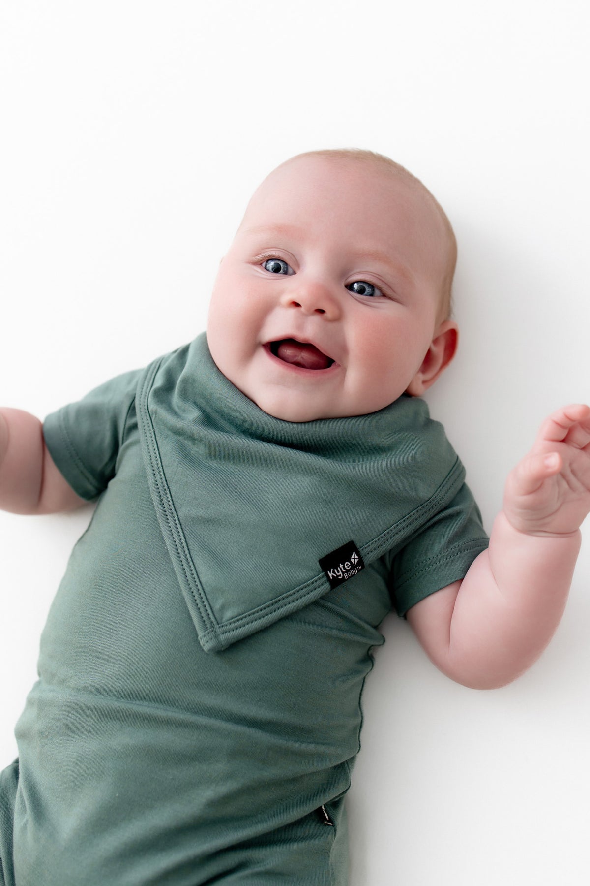 Baby wearing Bib in Pine over similar color bodysuit on a white background