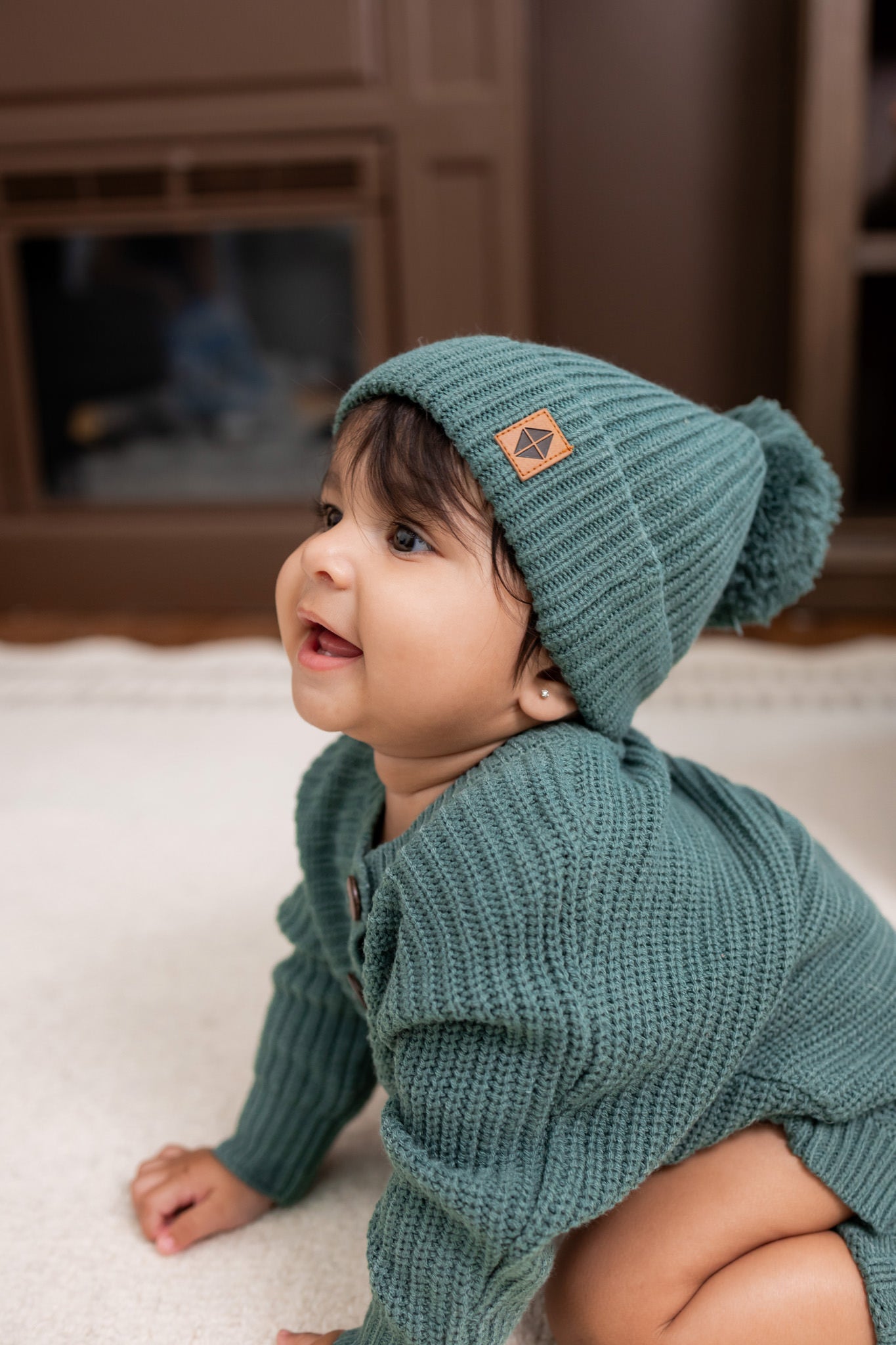 Baby wearing Chunky Knit Romper and chunky knit pom beanie in Pine