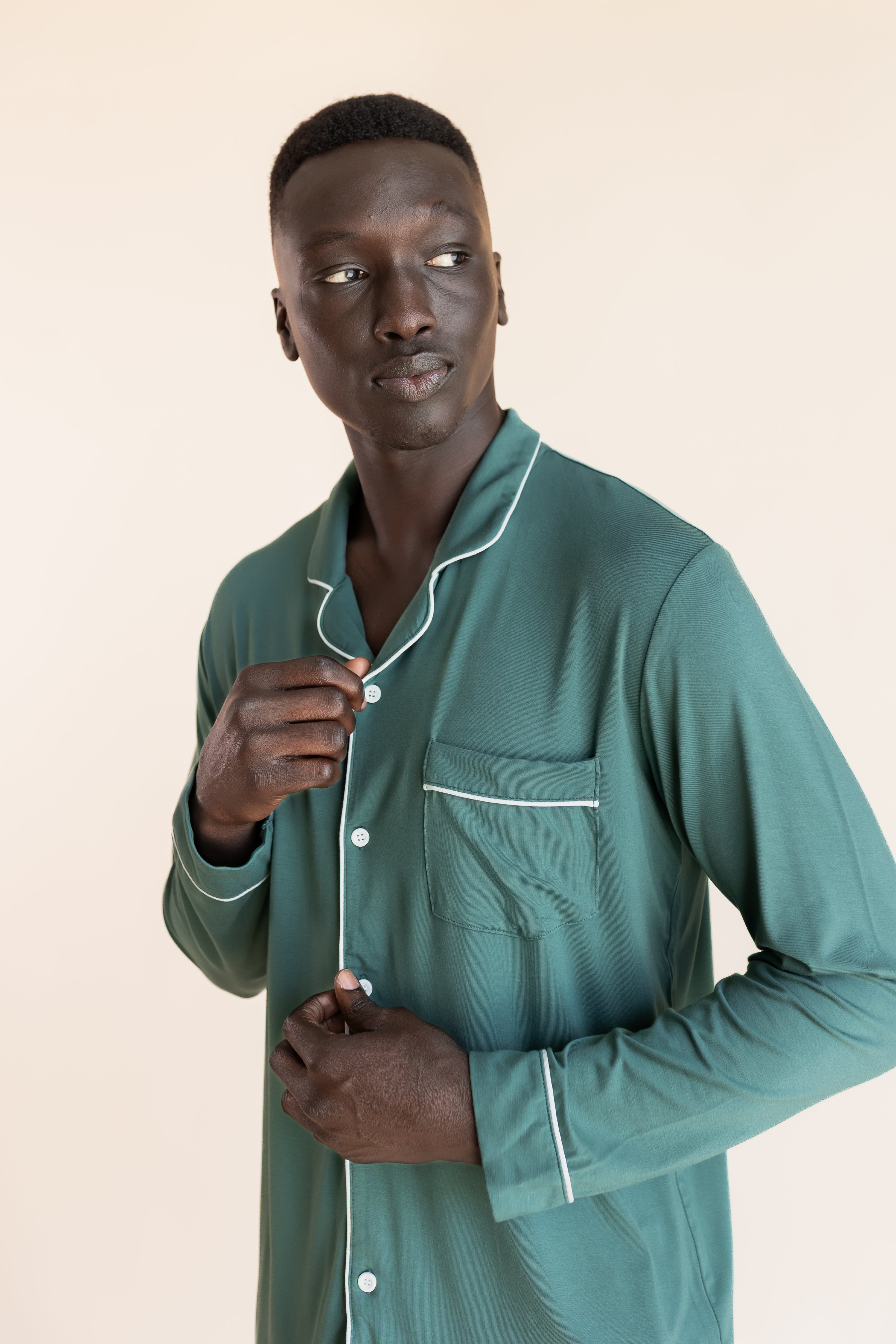 Close up of Model wearing Men's Long Sleeve Pajama Set in Pine on a beige background