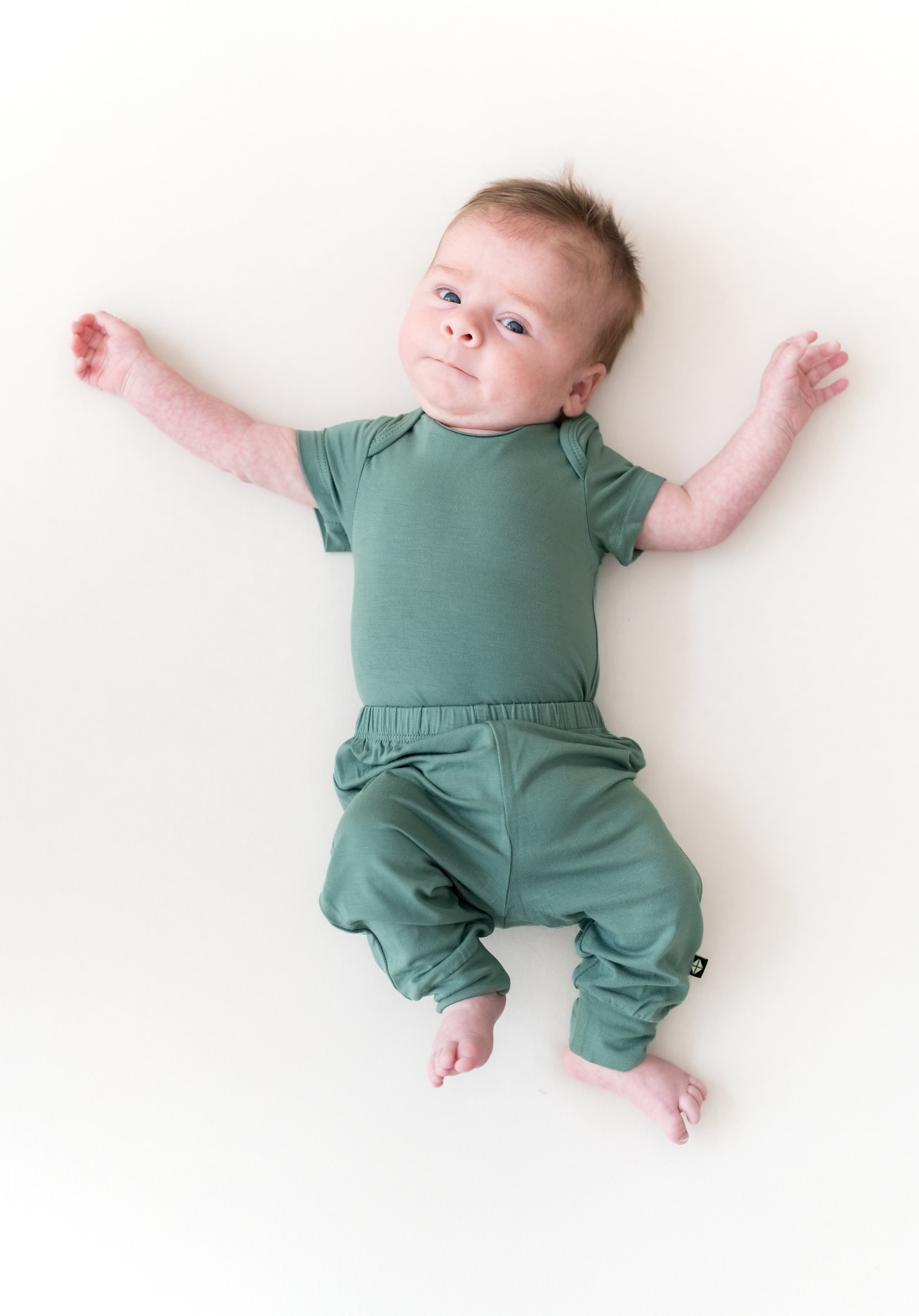 Baby wearing Pant in Pine over Pine bodysuit on a beige background