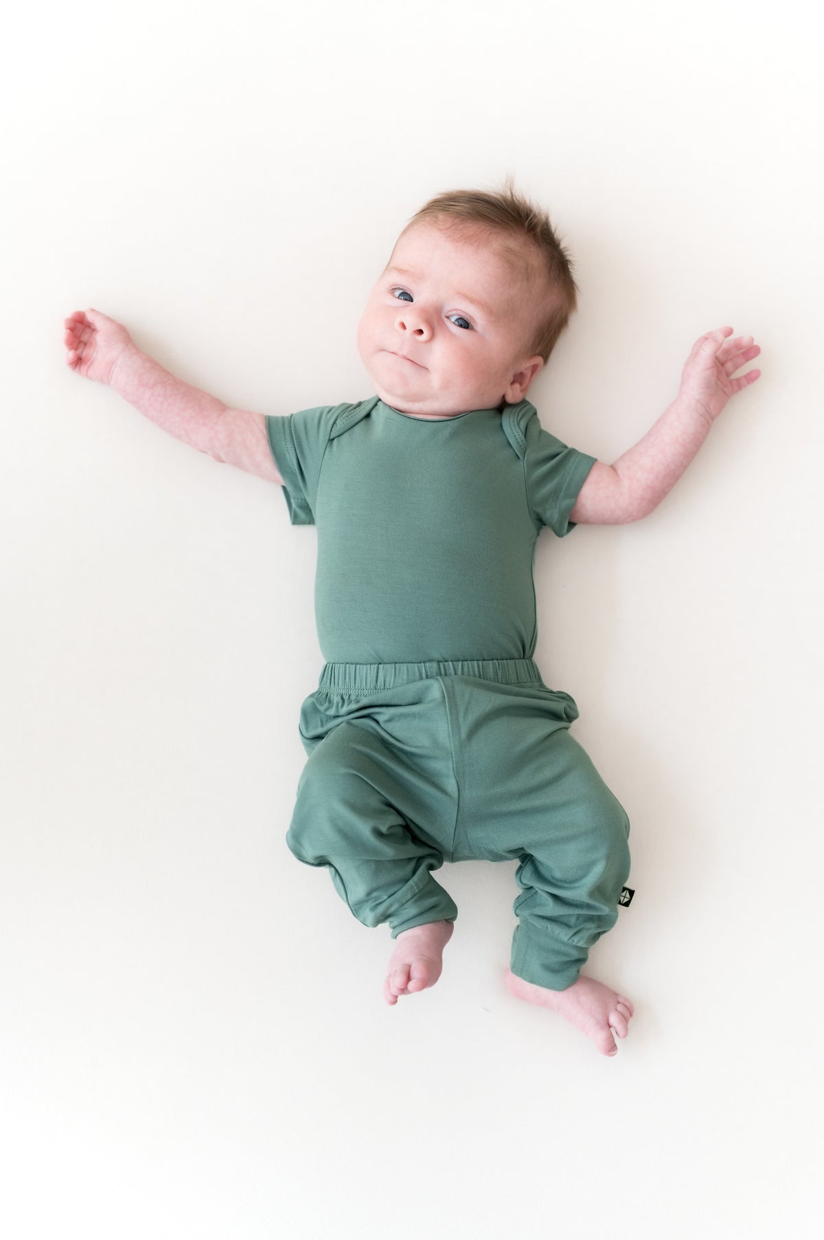 Baby wearing Pant in Pine over Pine bodysuit on a beige background