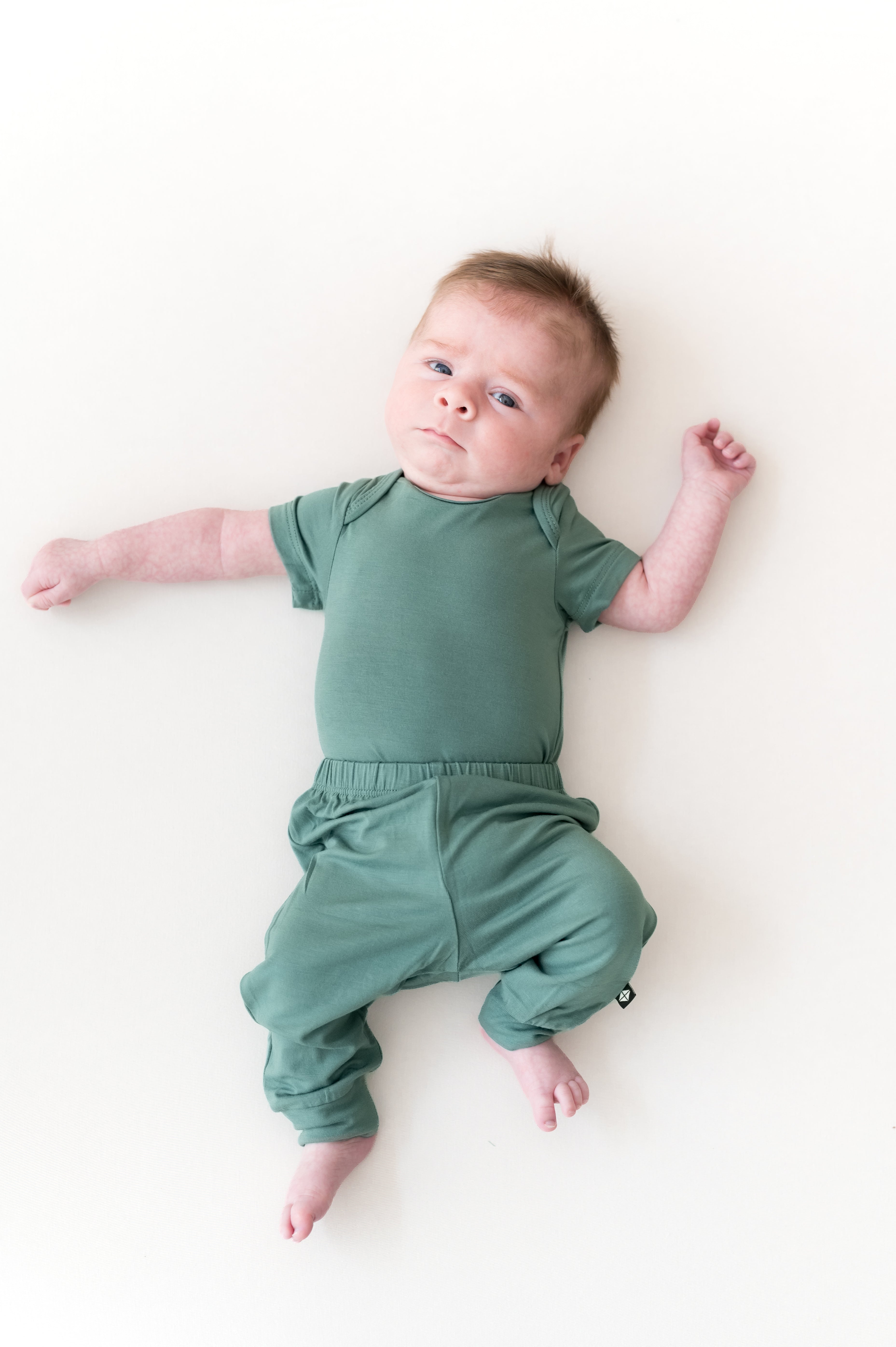 Baby wearing Pant in Pine over Pine bodysuit on a beige background
