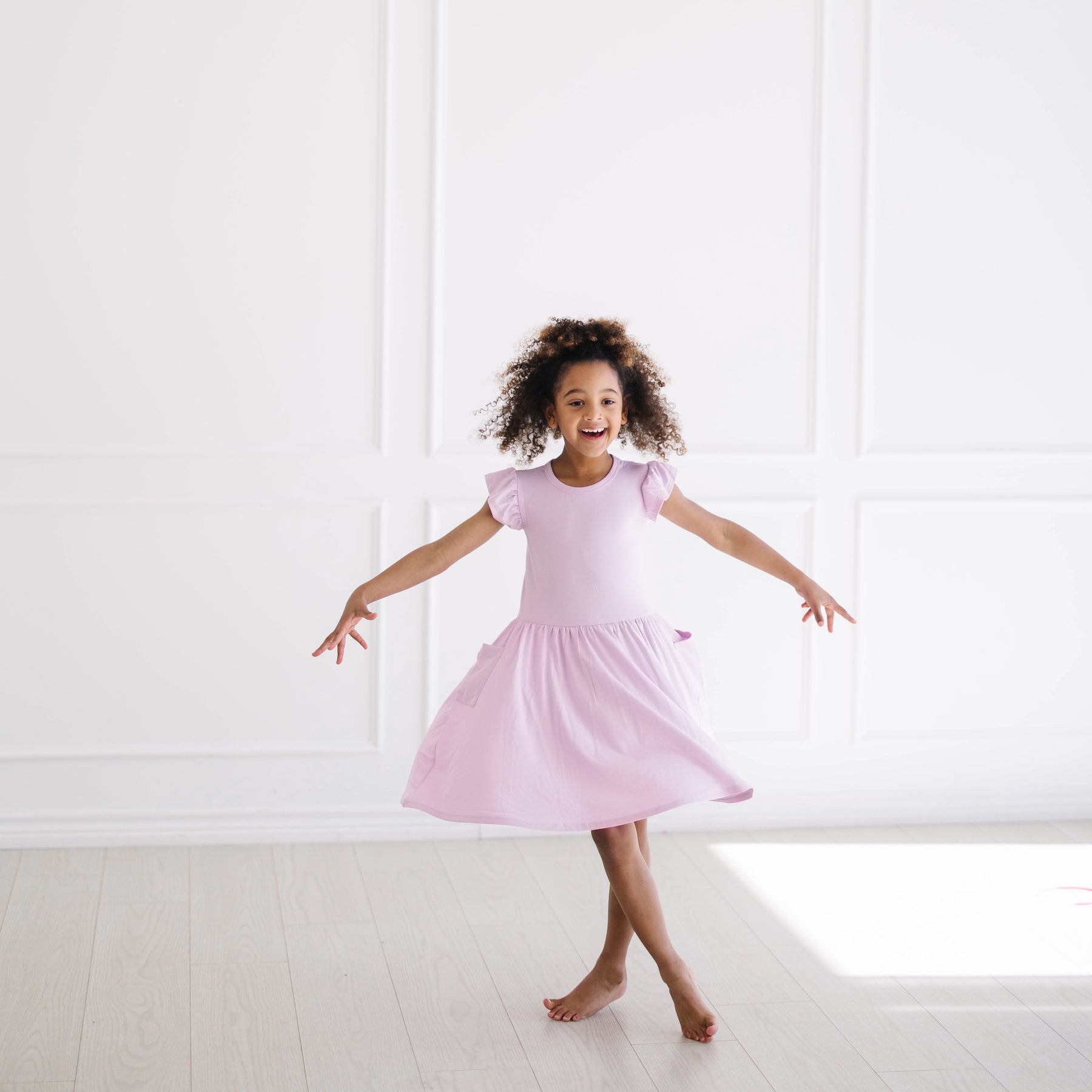 Young girl twirling wearing the Pocket Dress in Thistle