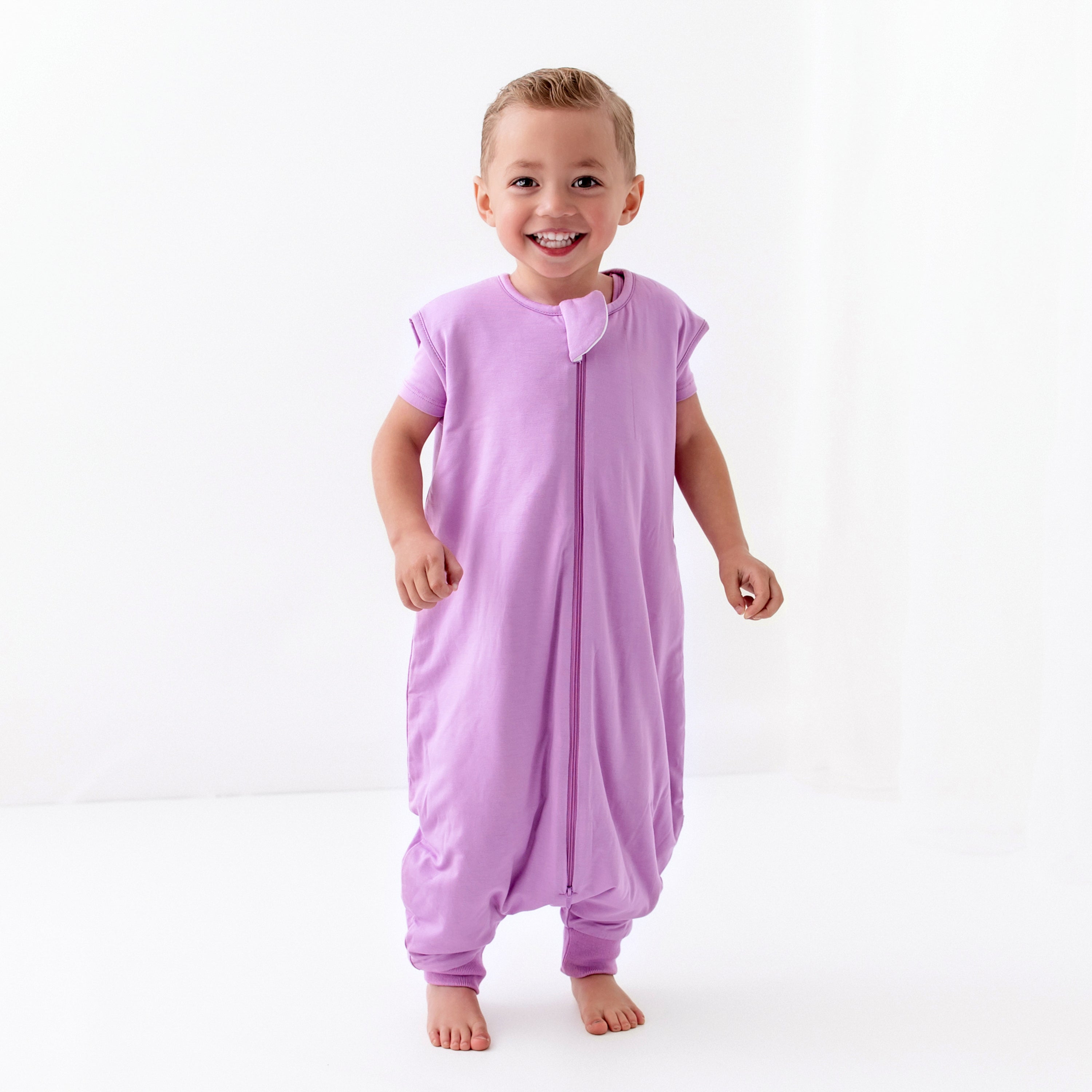 Young smiling child wearing the Sleep Bag Walker in Poi 1.0 with matching short sleeve pajamas