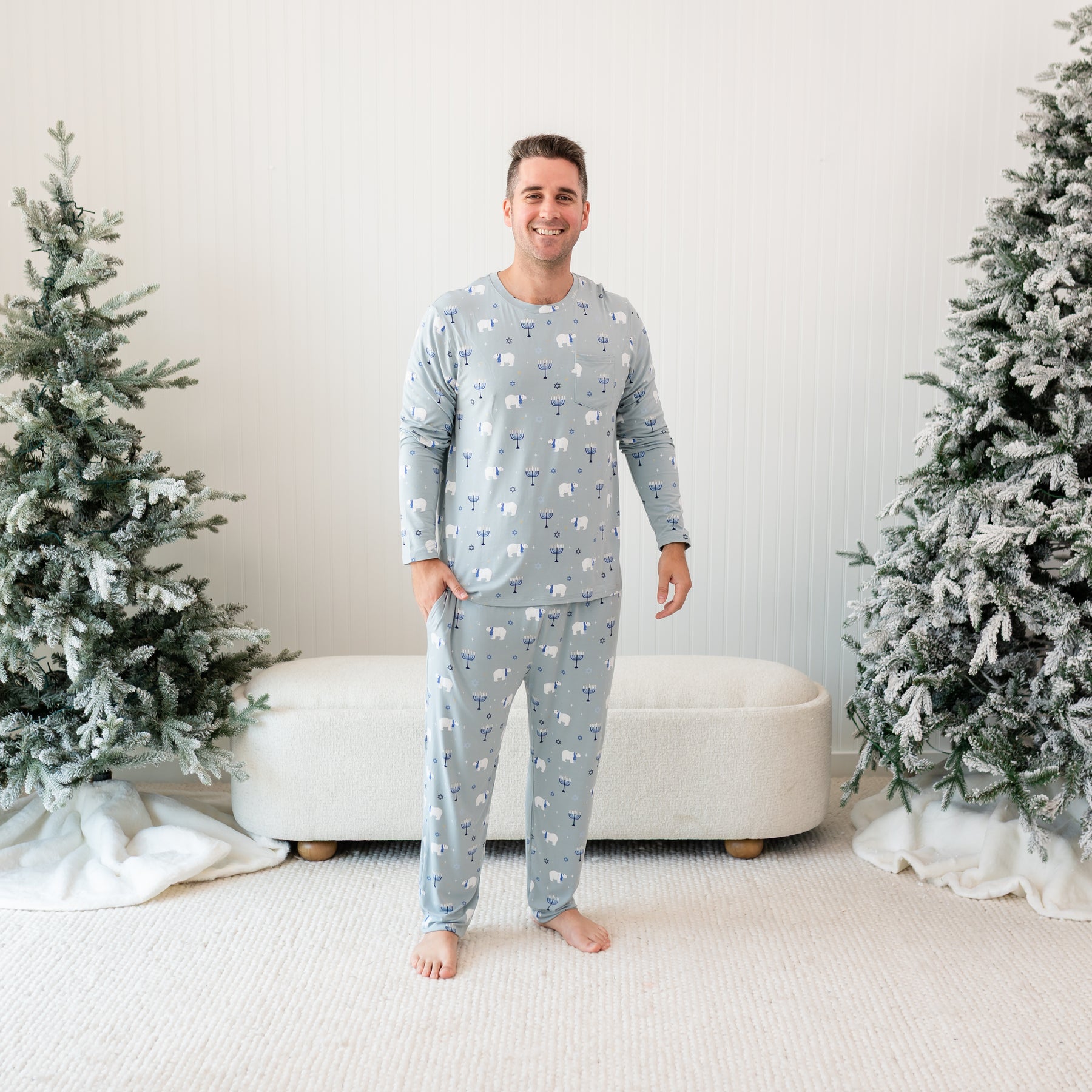 Smiling male model standing between two frosted trees wearing  the Men's Jogger Set in Polar Lights with one hand in the pants pocket