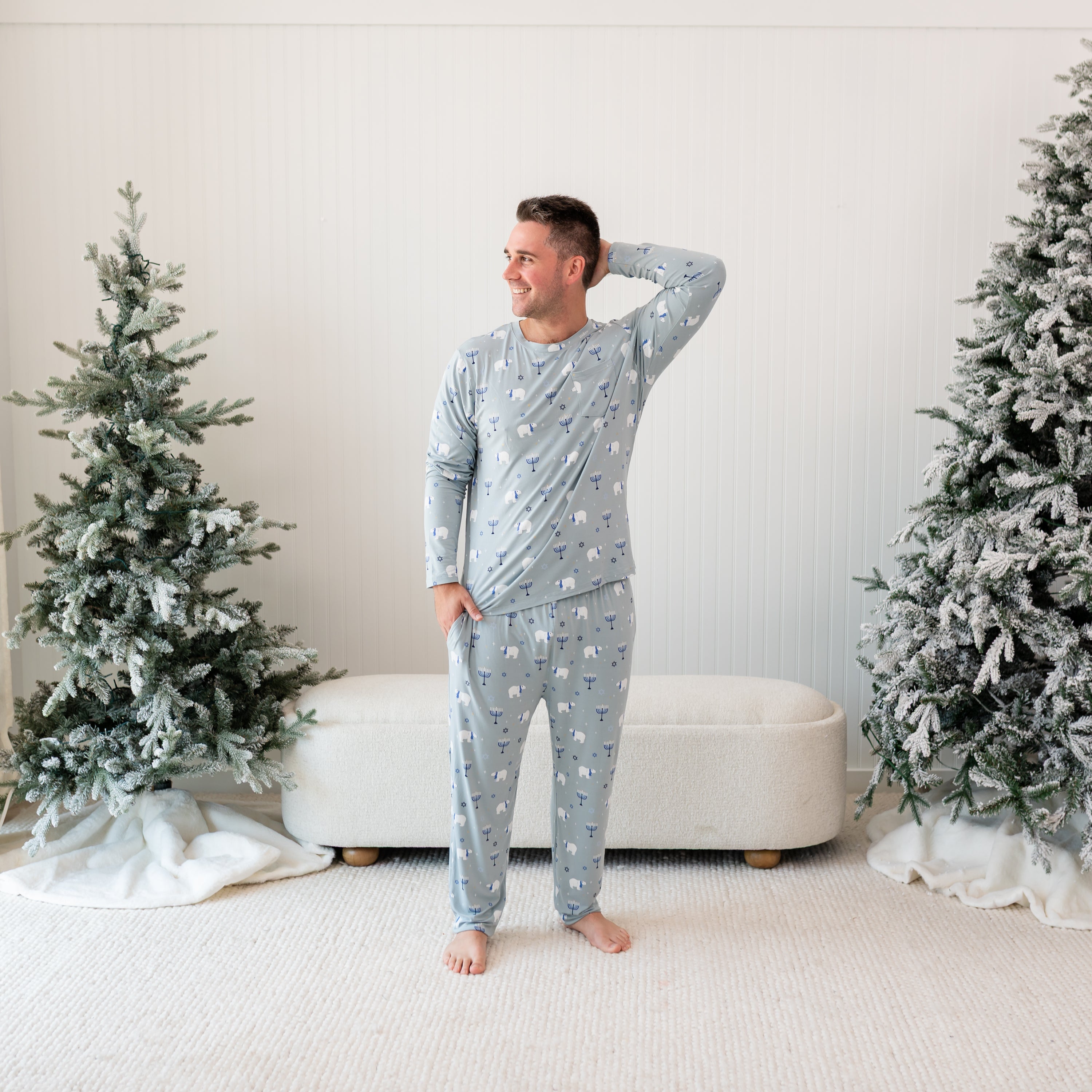 Male model standing between two frosted trees wearing the Men's Jogger Set in Polar Lights with one hand in pants pocket and the other behind his head