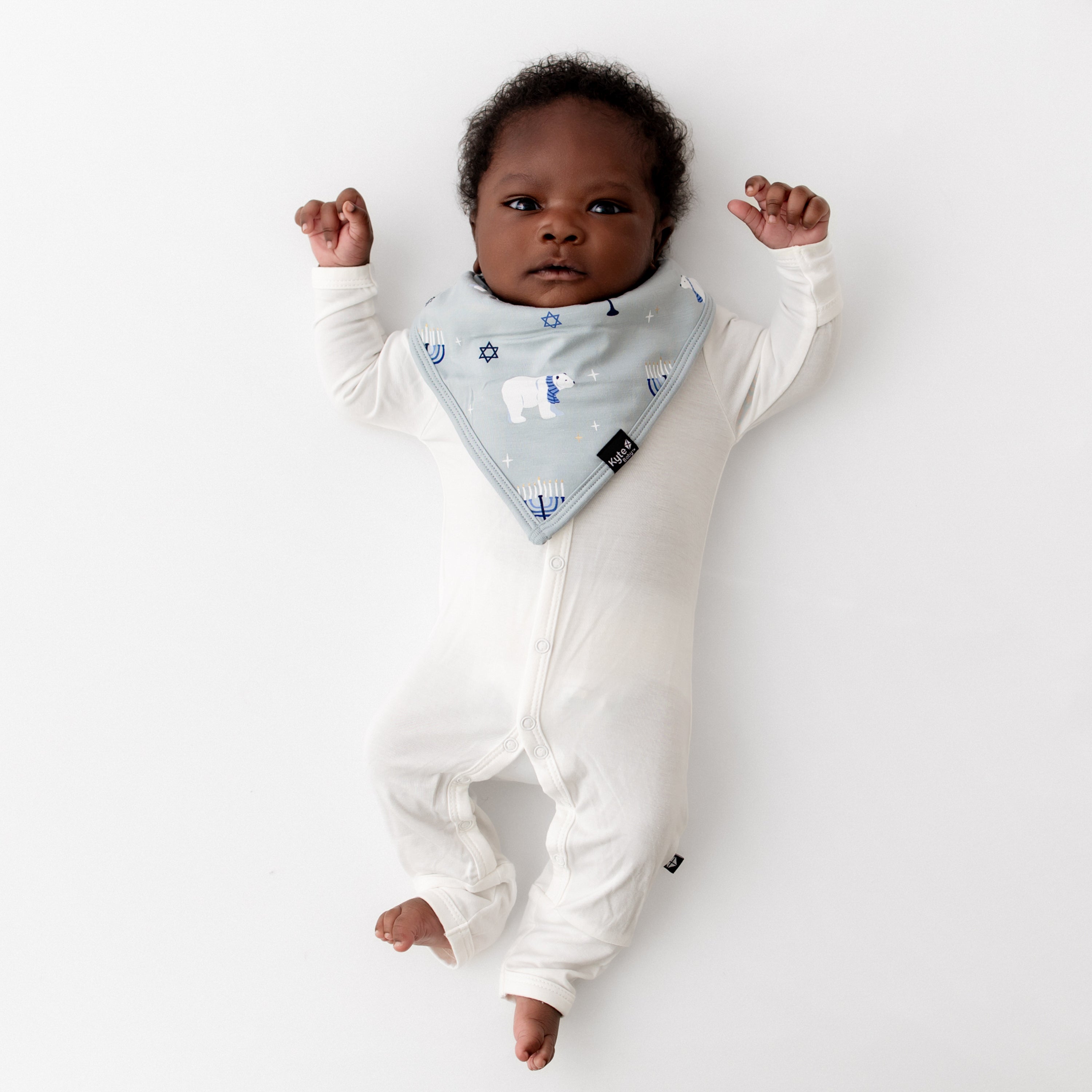 Newborn laying on a white background wearing the Bib in Polar Lights with a Cloud Snap romper
