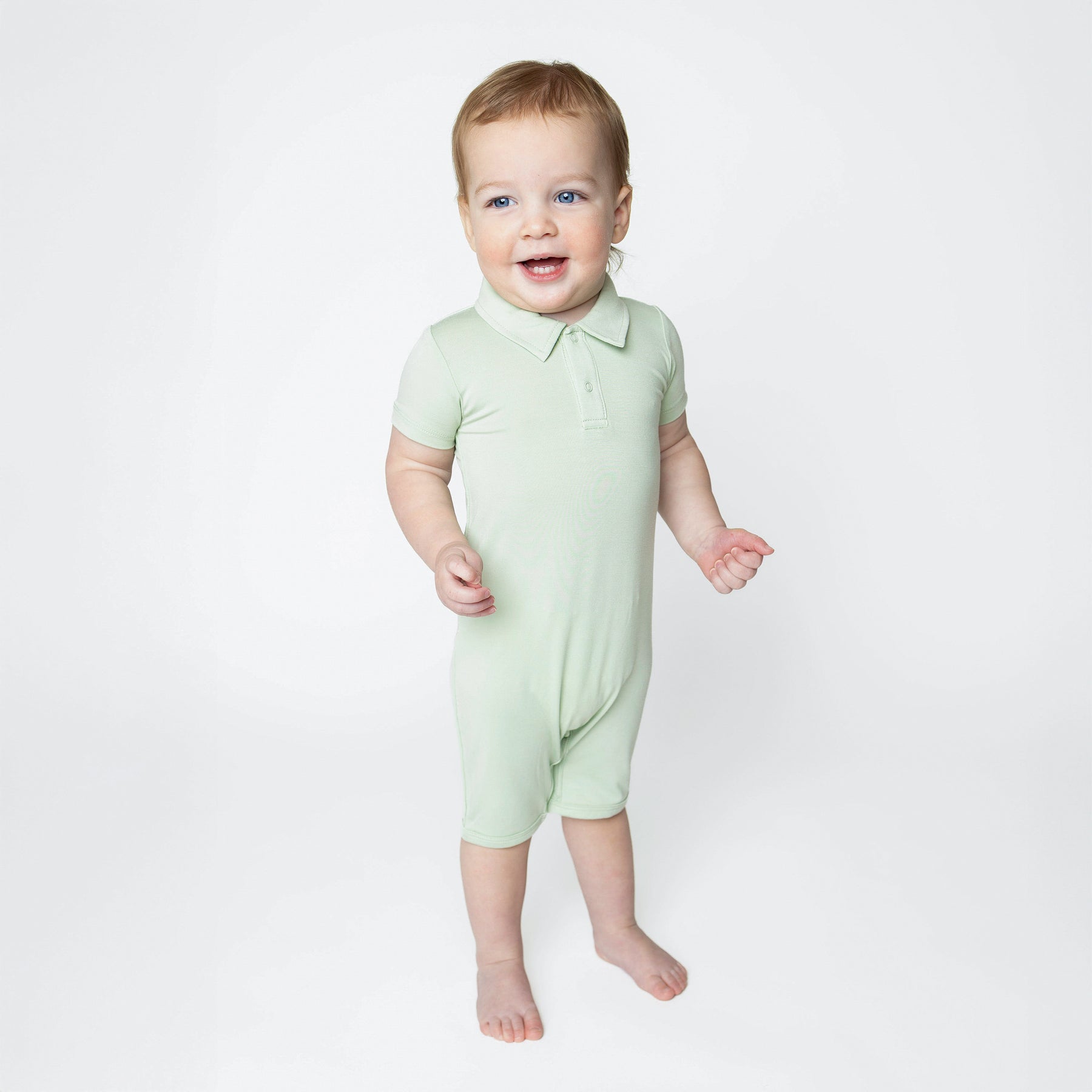 Young toddler wearing the Polo Shortall in Basil standing in front of a white background