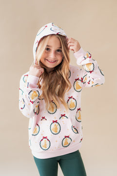 Girl wearing Hoodie in Princess Holiday Portraits print over green leggings on a beige background