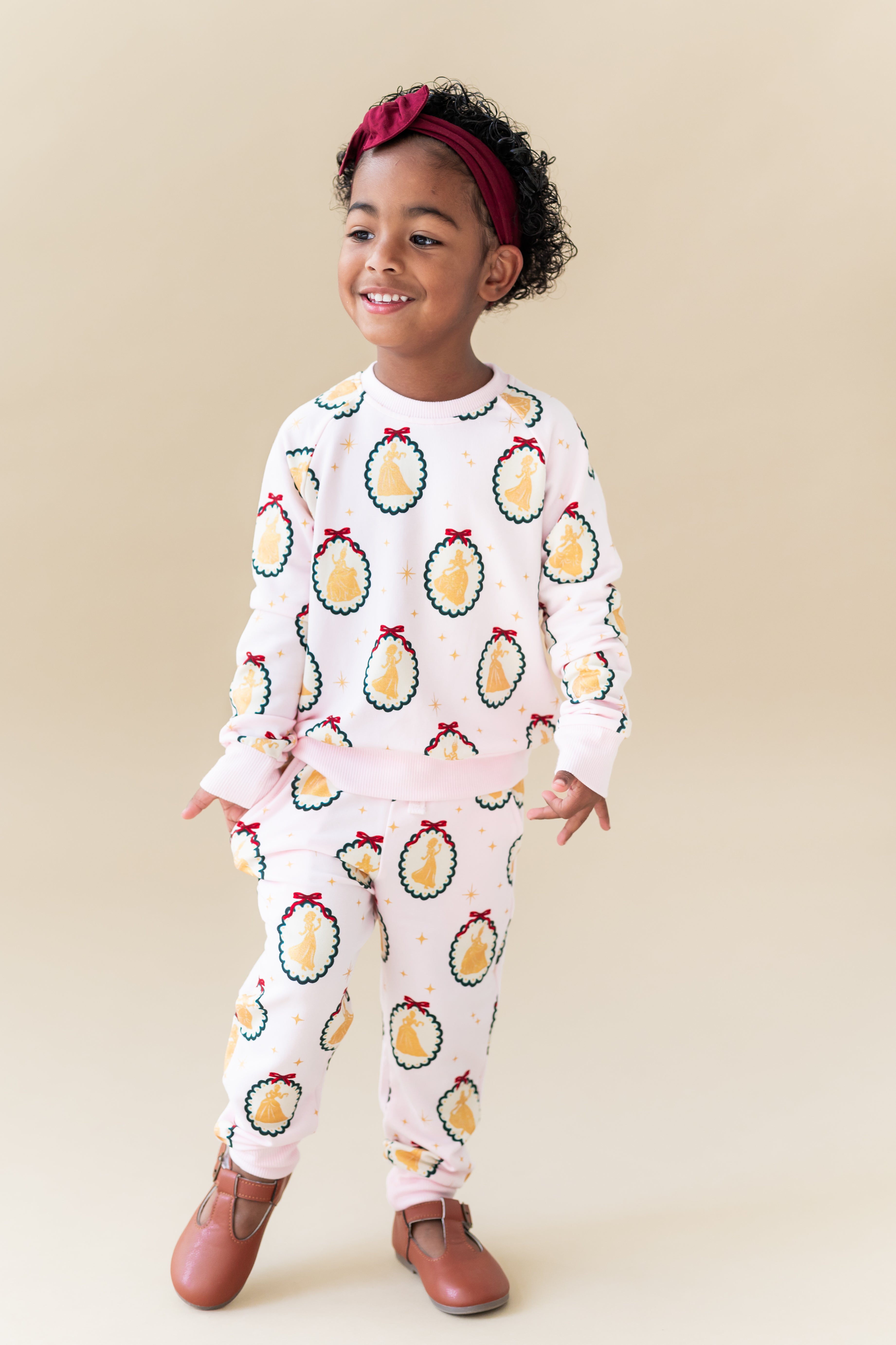 Child wearing Long Sleeve Jogger Set in Princess Holiday Portraits print on a beige background