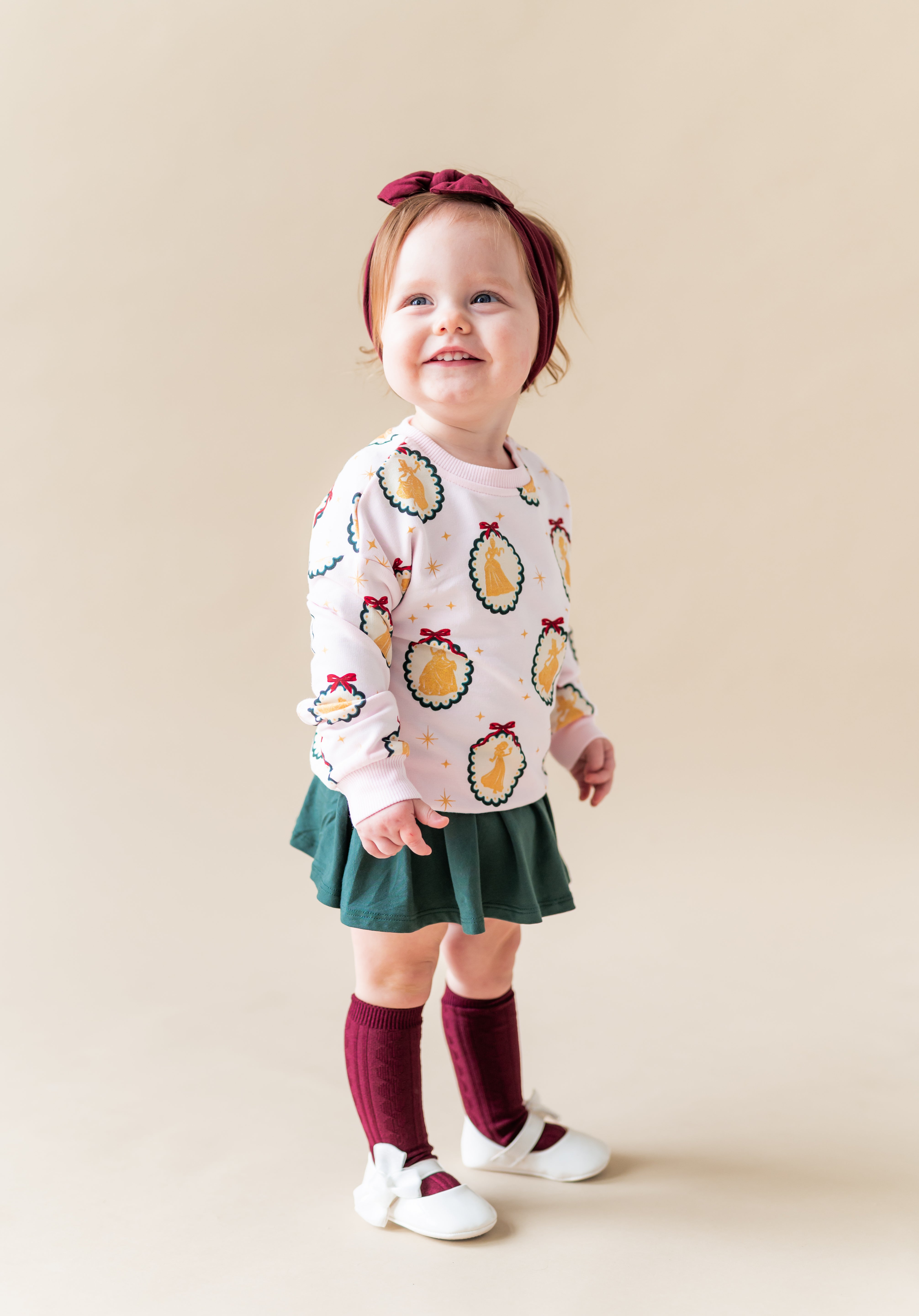 Girl wearing Sweatshirt in Princess Holiday Portraits print over green skirt on a beige background