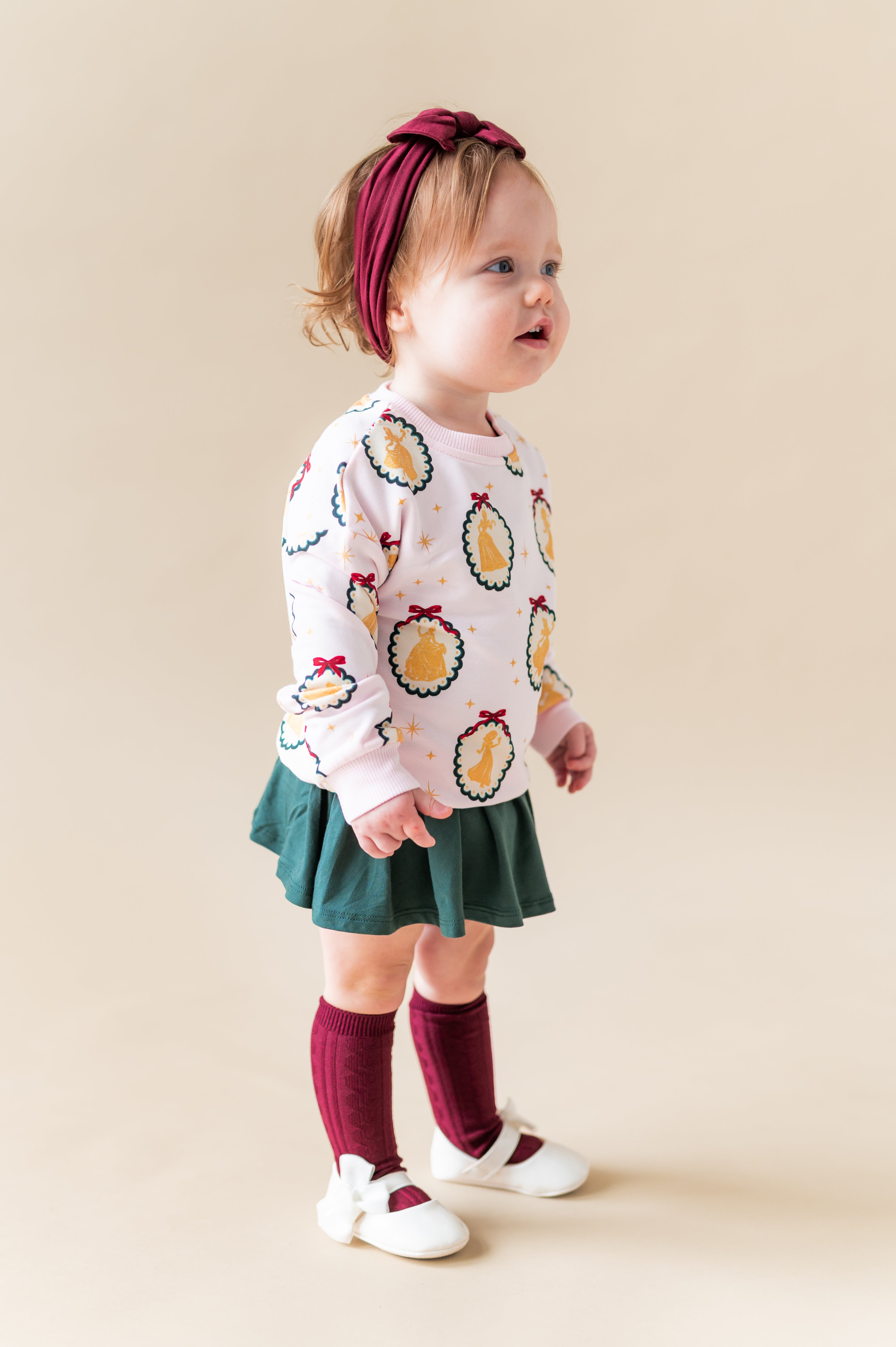 Girl wearing Sweatshirt in Princess Holiday Portraits print over green skirt on a beige background