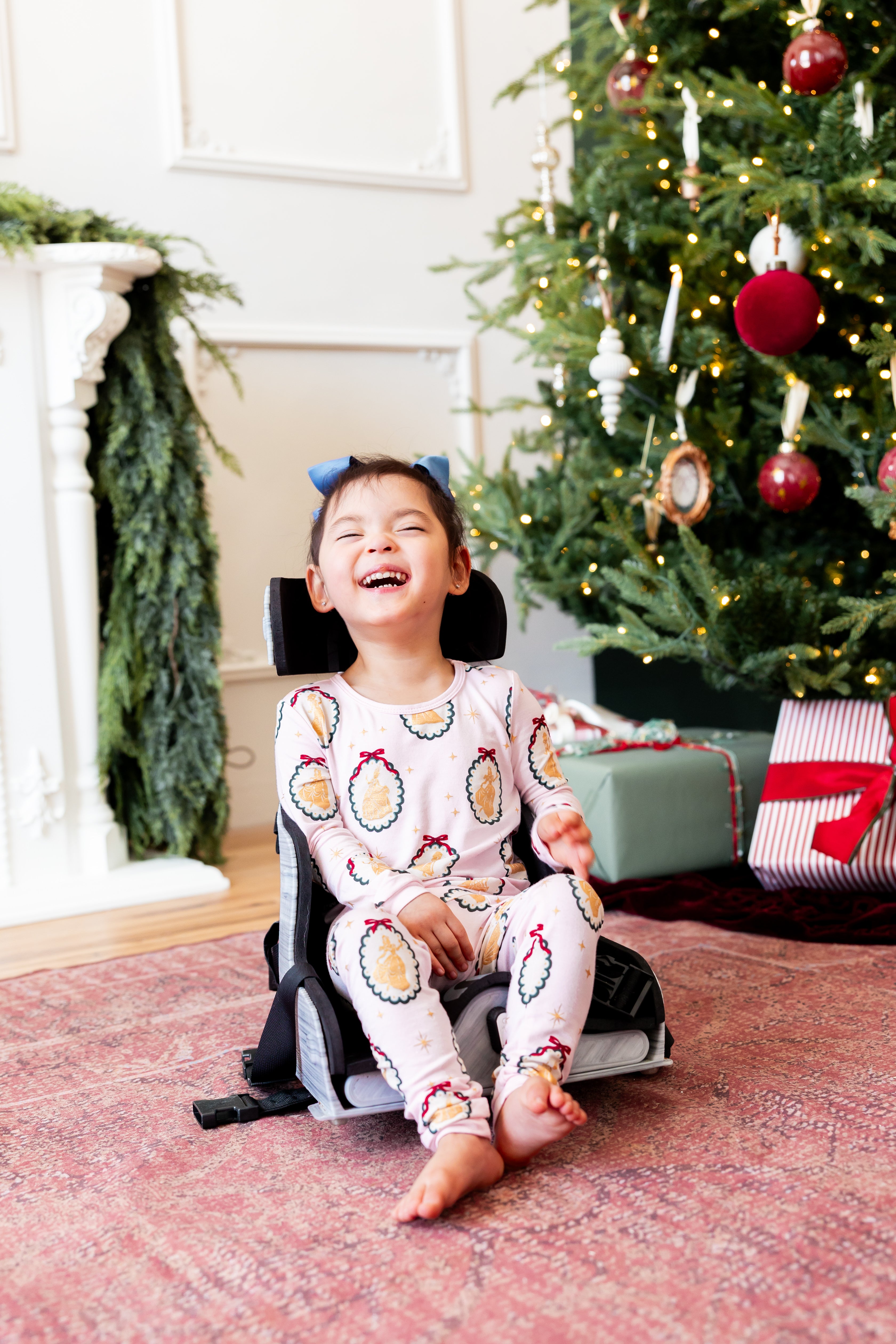 Girl wearing Long Sleeve Pajamas in Princess Holiday Portraits print sitting in front of Christmas tree