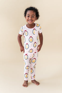 Child wearing Short Sleeve with Pants Pajamas in Princess Holiday Portraits print on a beige background