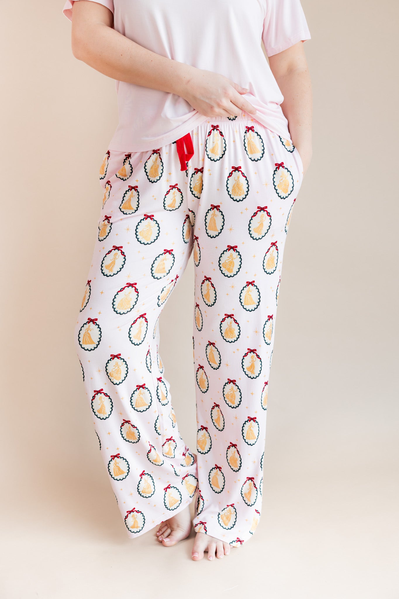 Modal wearing Women's Lounge Pants in Princess Holiday Portraits print under pink T-shirt on a beige background