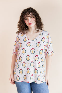 Woman wearing Women's Oversized V-Neck Tee in Princess Holiday Portraits print over blue jeans on a beige background