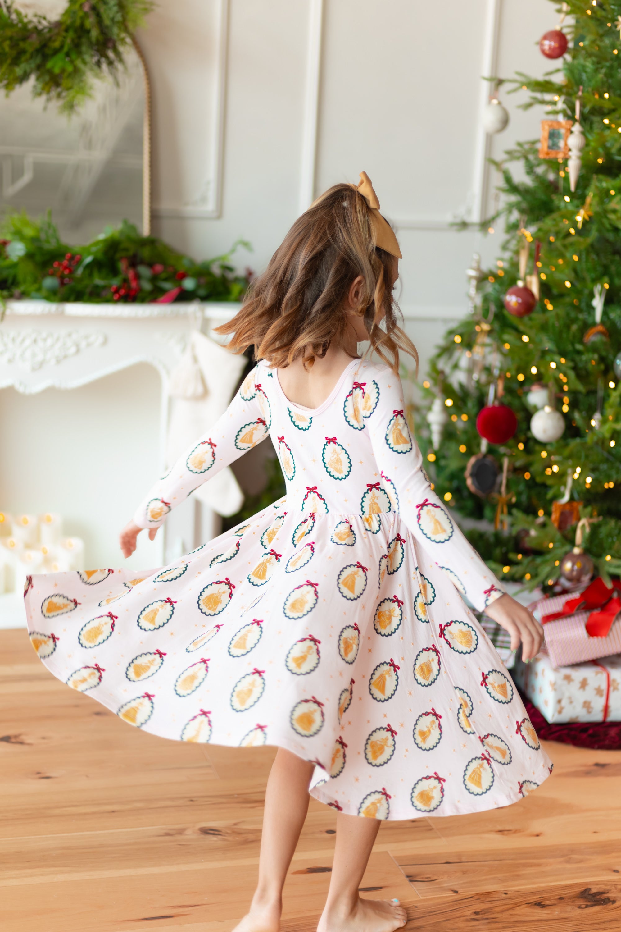 Girl twirling in Long Sleeve Twirl Dress in Princess Holiday Portraits print in front of Christmas tree and presents