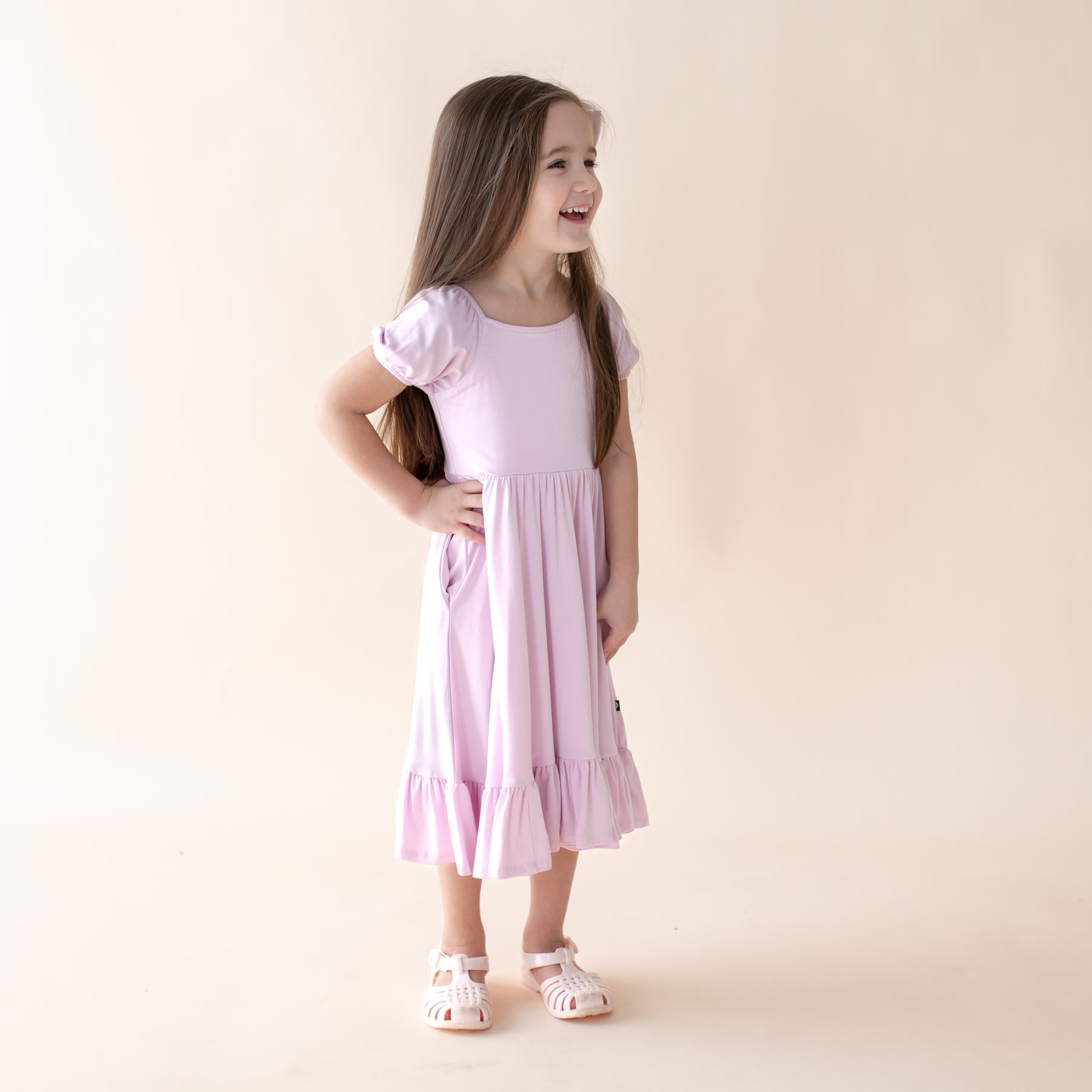 Young girl wearing a light purple dress on a beige background