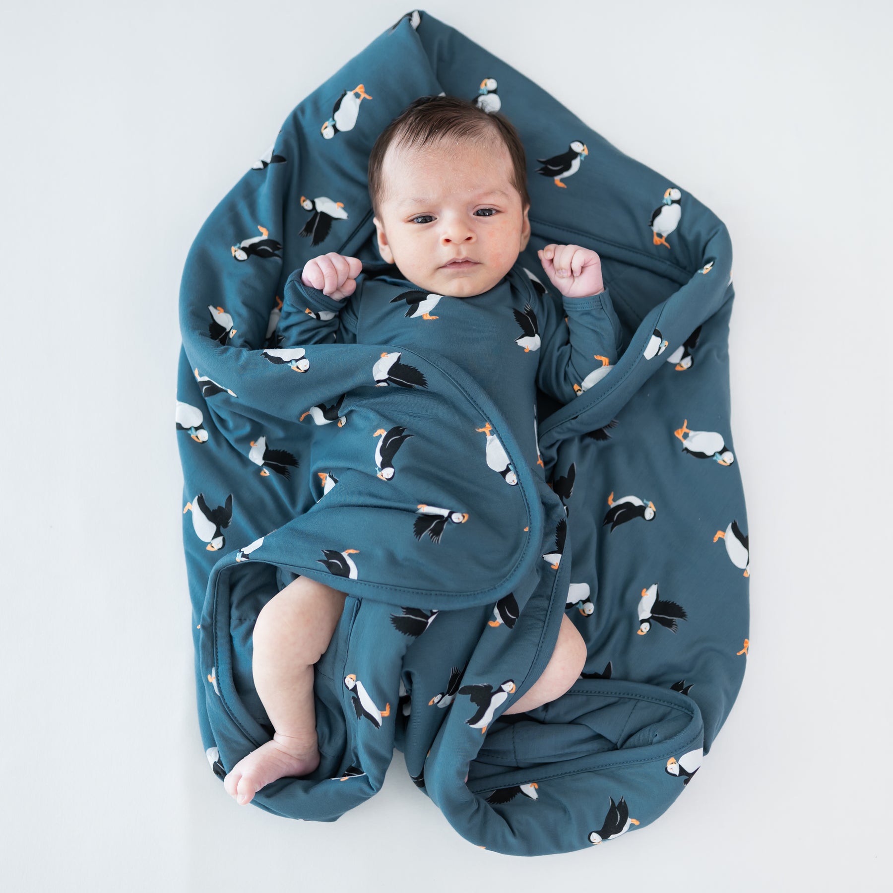 Baby laying on a Baby Blanket in Puffin wearing a matching long sleeve bodysuit