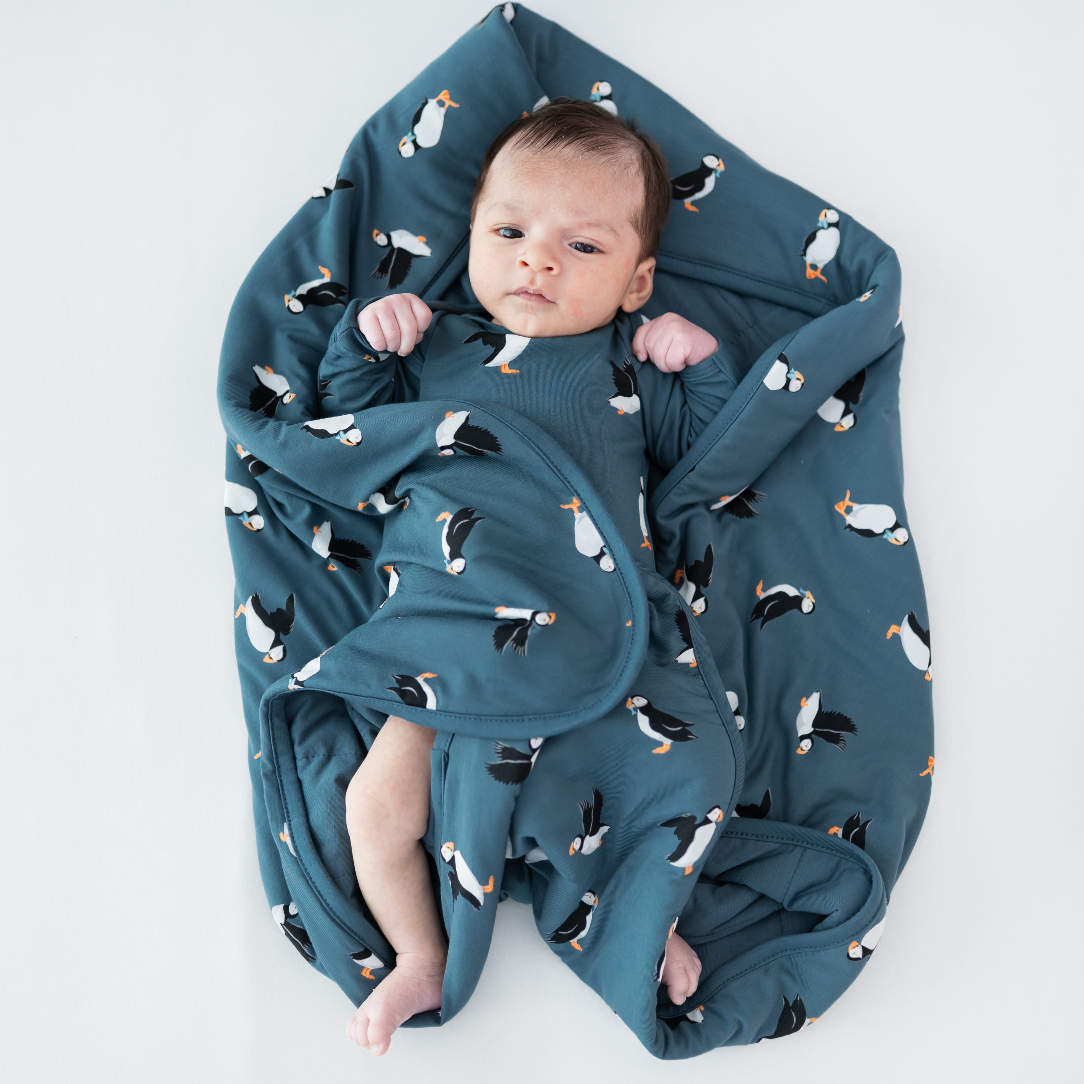 Baby laying on a Baby Blanket in Puffin wearing a matching long sleeve bodysuit