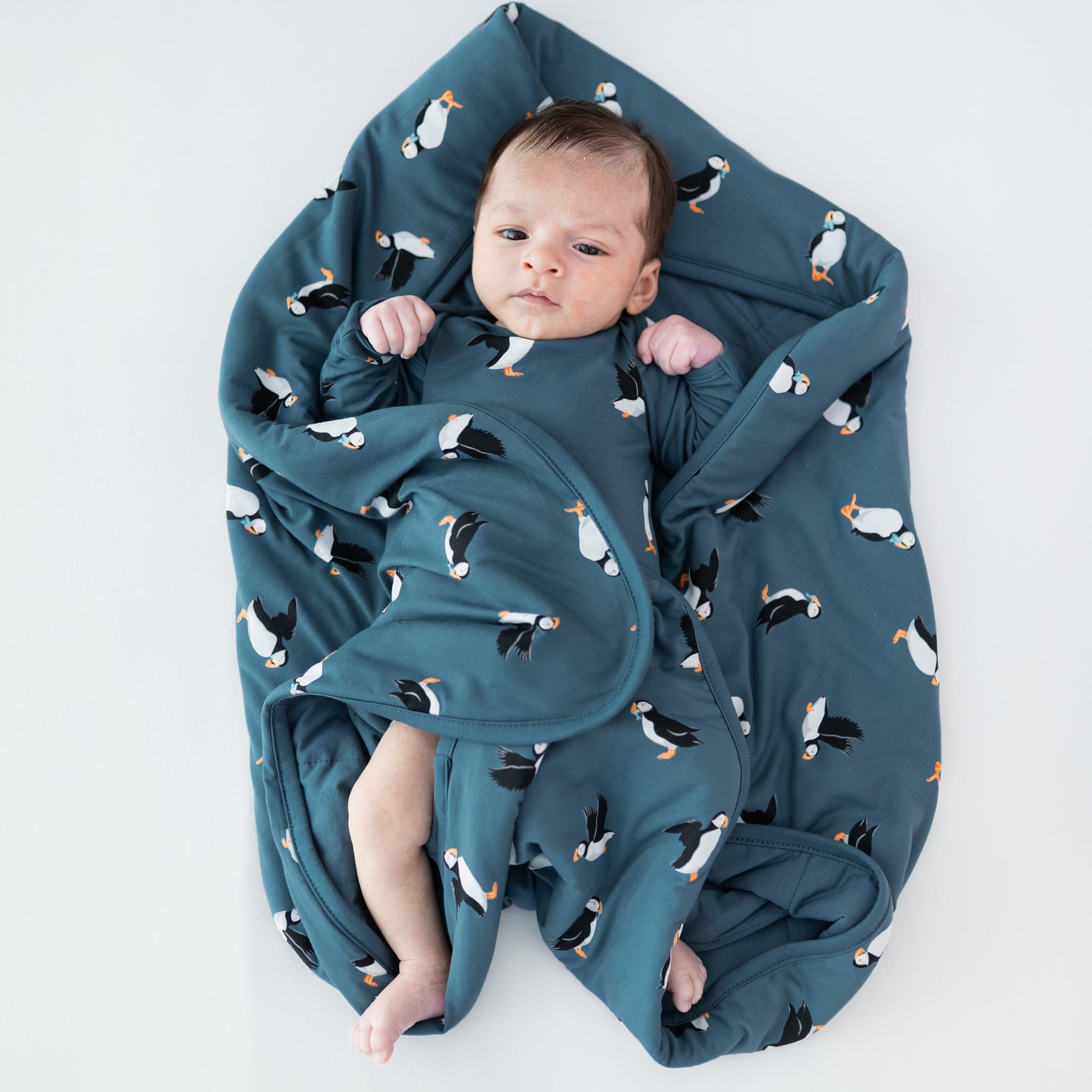 Baby laying on a Baby Blanket in Puffin wearing a matching long sleeve bodysuit