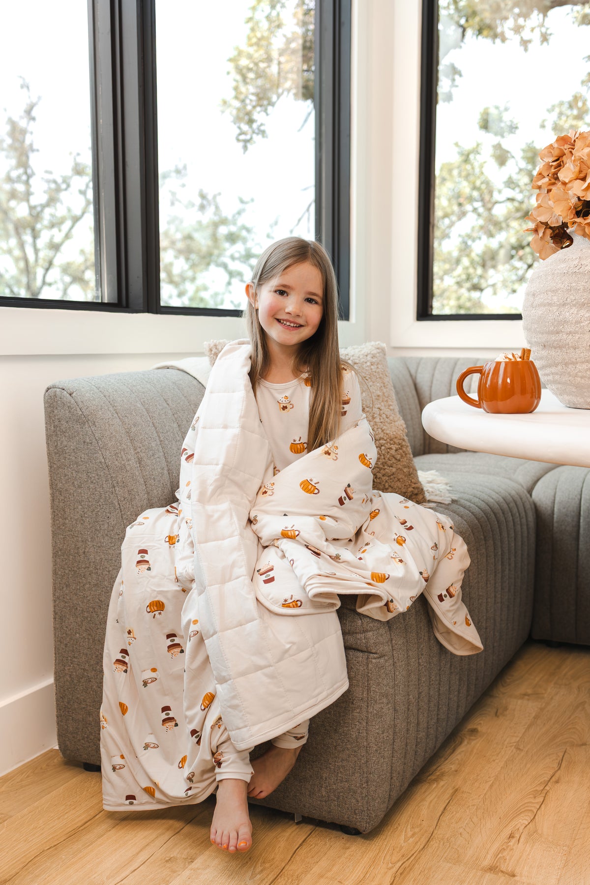 Girl smiling wrapped in Youth Blanket in Pumpkin Spice Latte 2.5 on a sofa