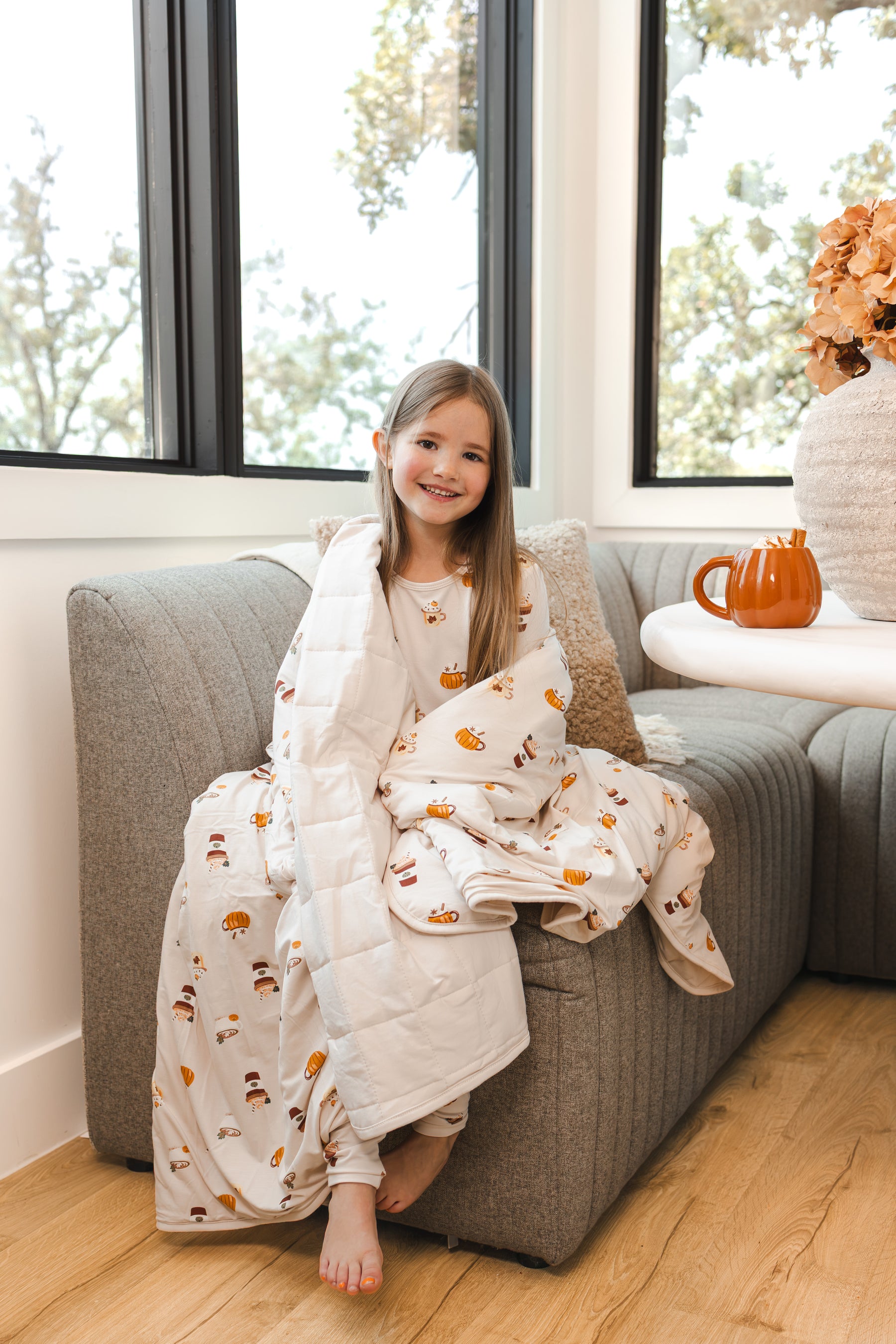 Girl smiling wrapped in Youth Blanket in Pumpkin Spice Latte 2.5 on a sofa