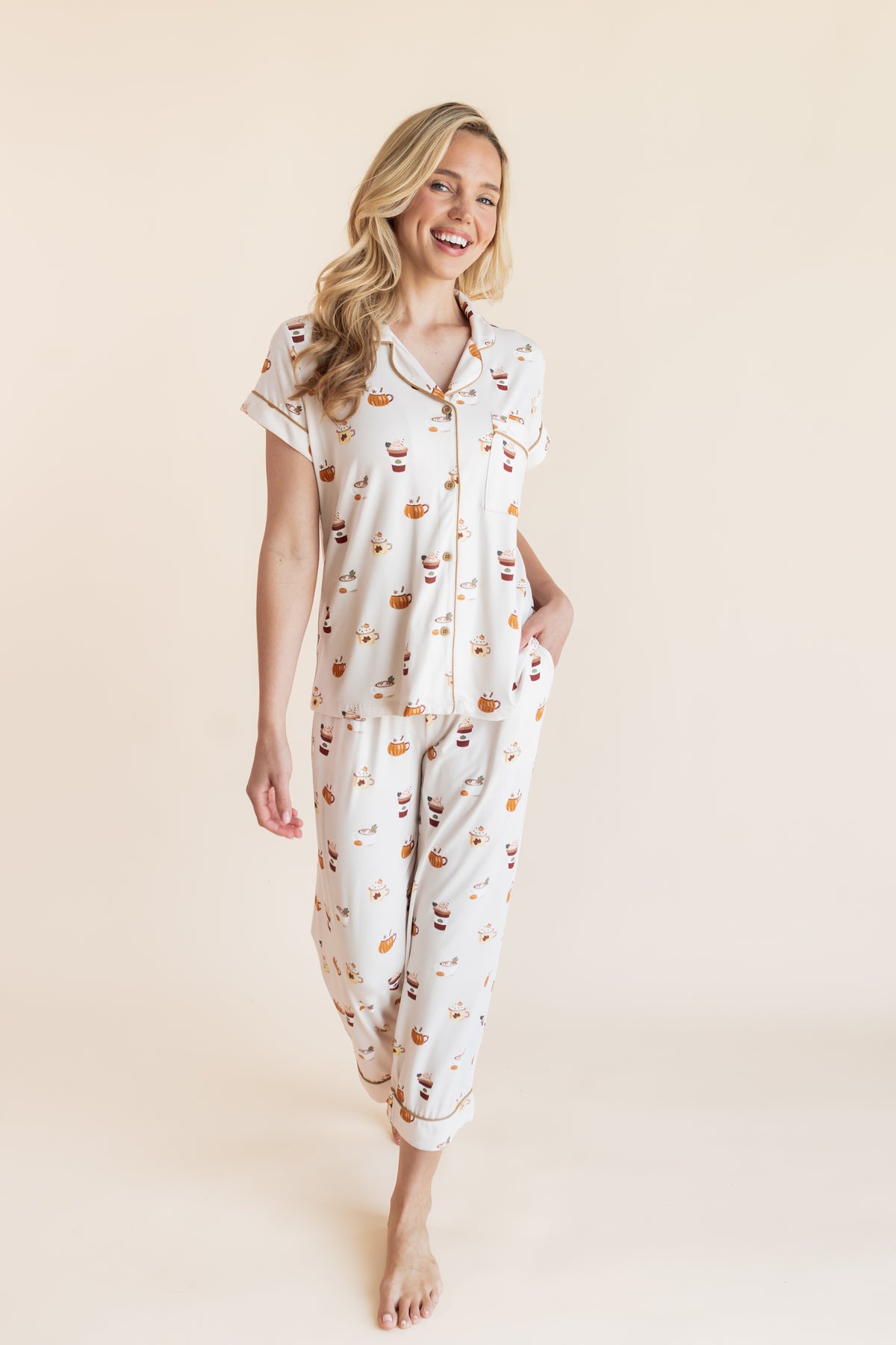 Modal posing in Women's Short Sleeve Cropped Pajama Set with Pumpkin Spice Latte print on a beige background