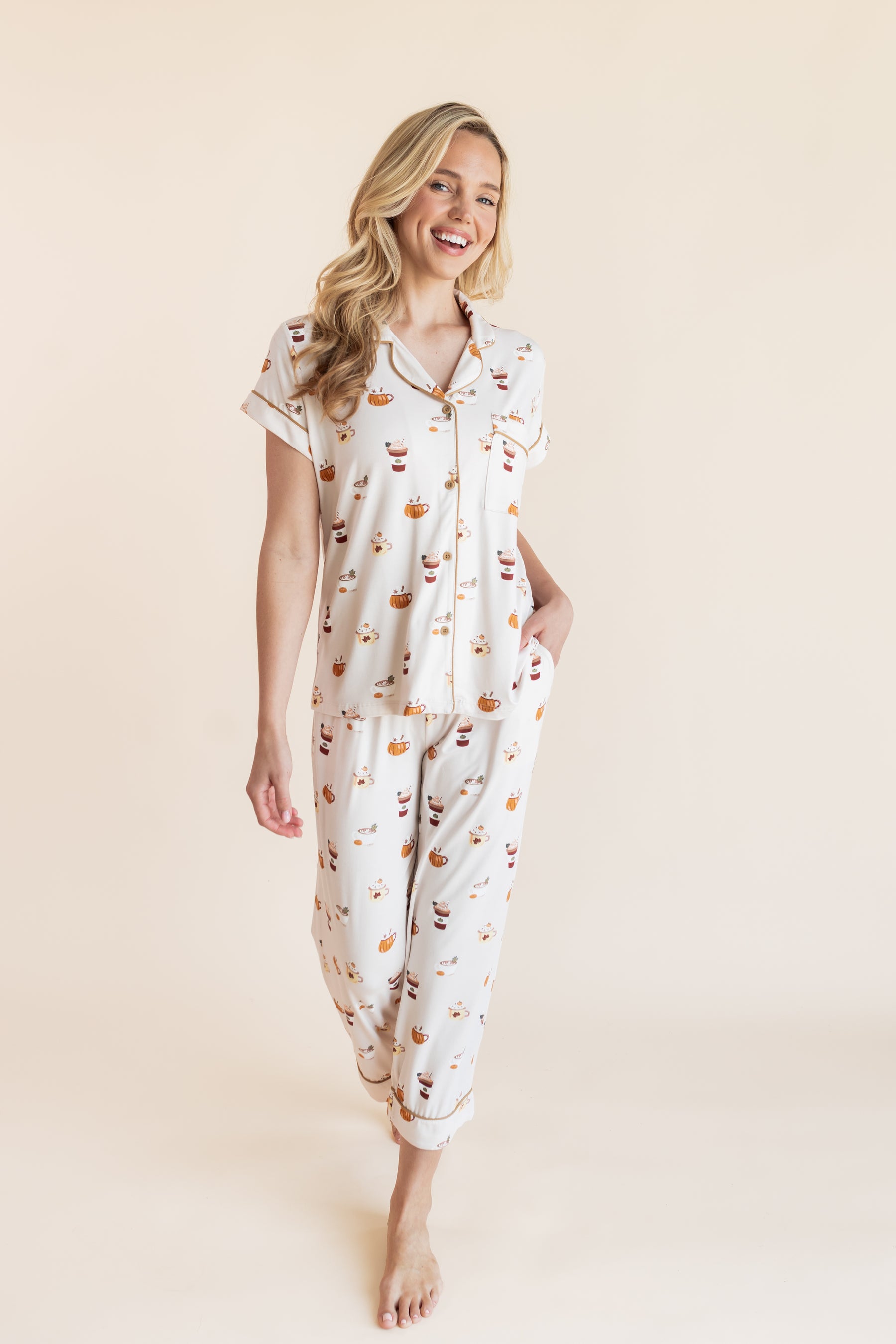 Modal posing in Women's Short Sleeve Cropped Pajama Set with Pumpkin Spice Latte print on a beige background