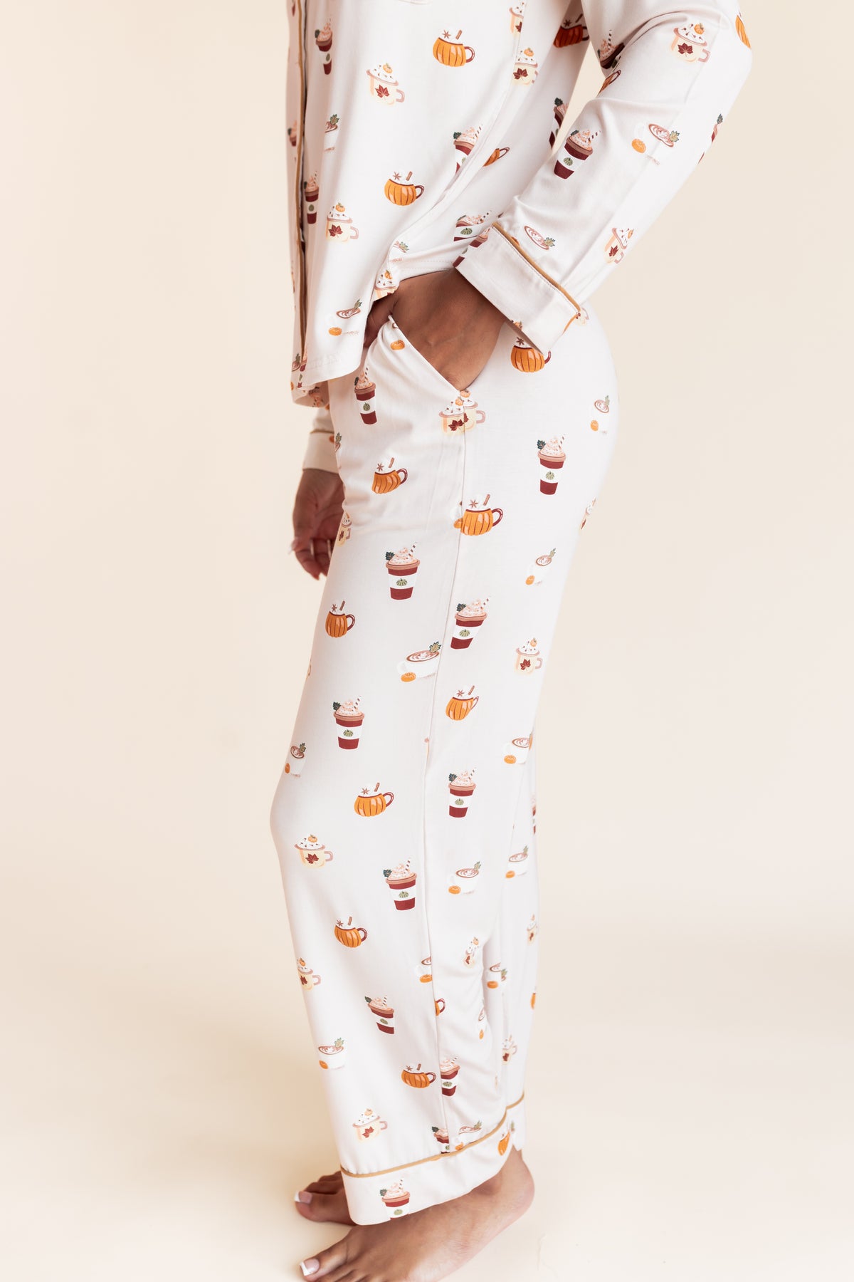 Model showcasing the pocket on Long-Sleeved Women's Pajama Set with Pumpkin Spice Latte print on a beige background