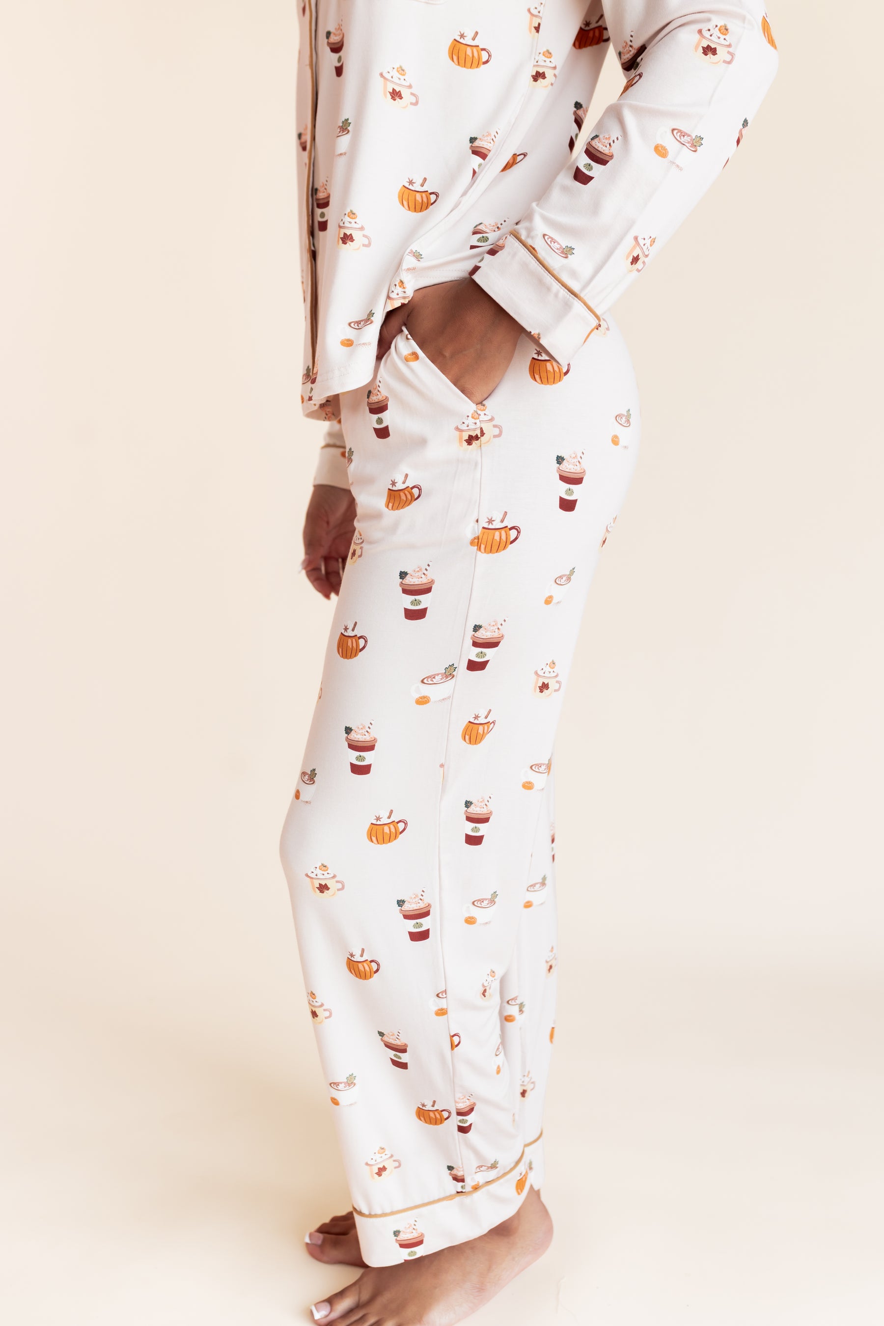Model showcasing the pocket on Long-Sleeved Women's Pajama Set with Pumpkin Spice Latte print on a beige background