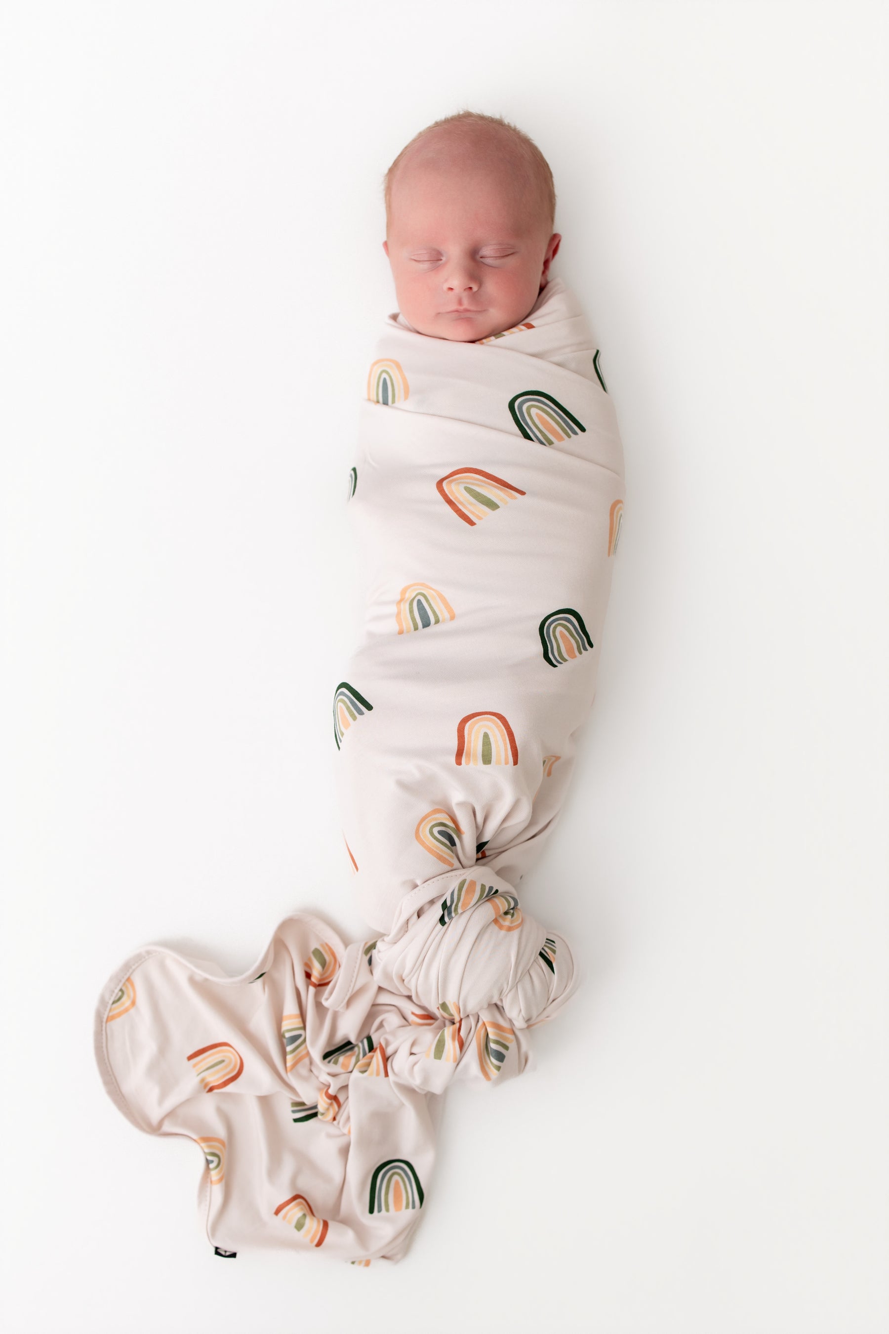 Baby sleeping in Swaddle Blanket in Retro Rainbow print on white background