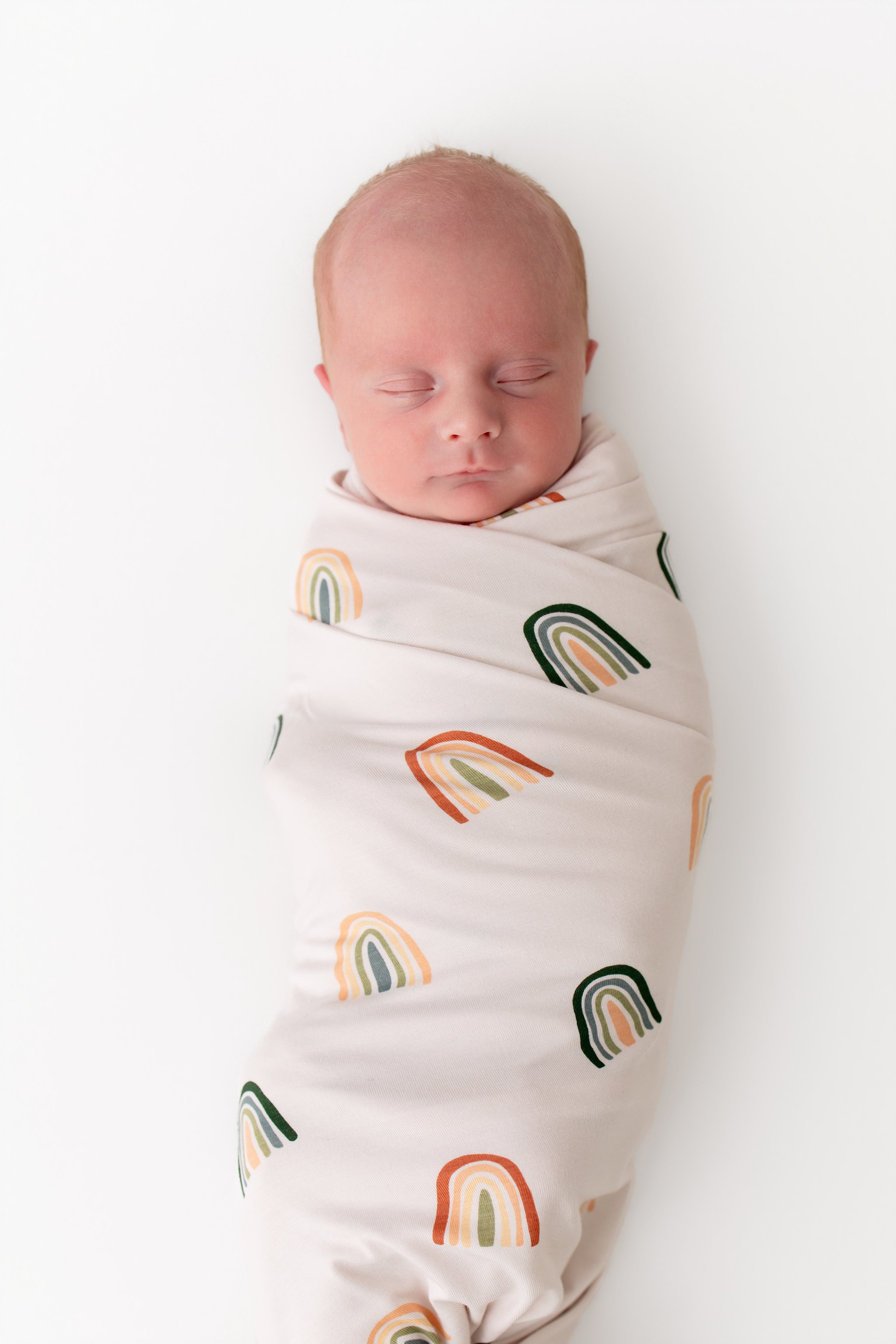 Baby sleeping in Swaddle Blanket in Retro Rainbow print on white background