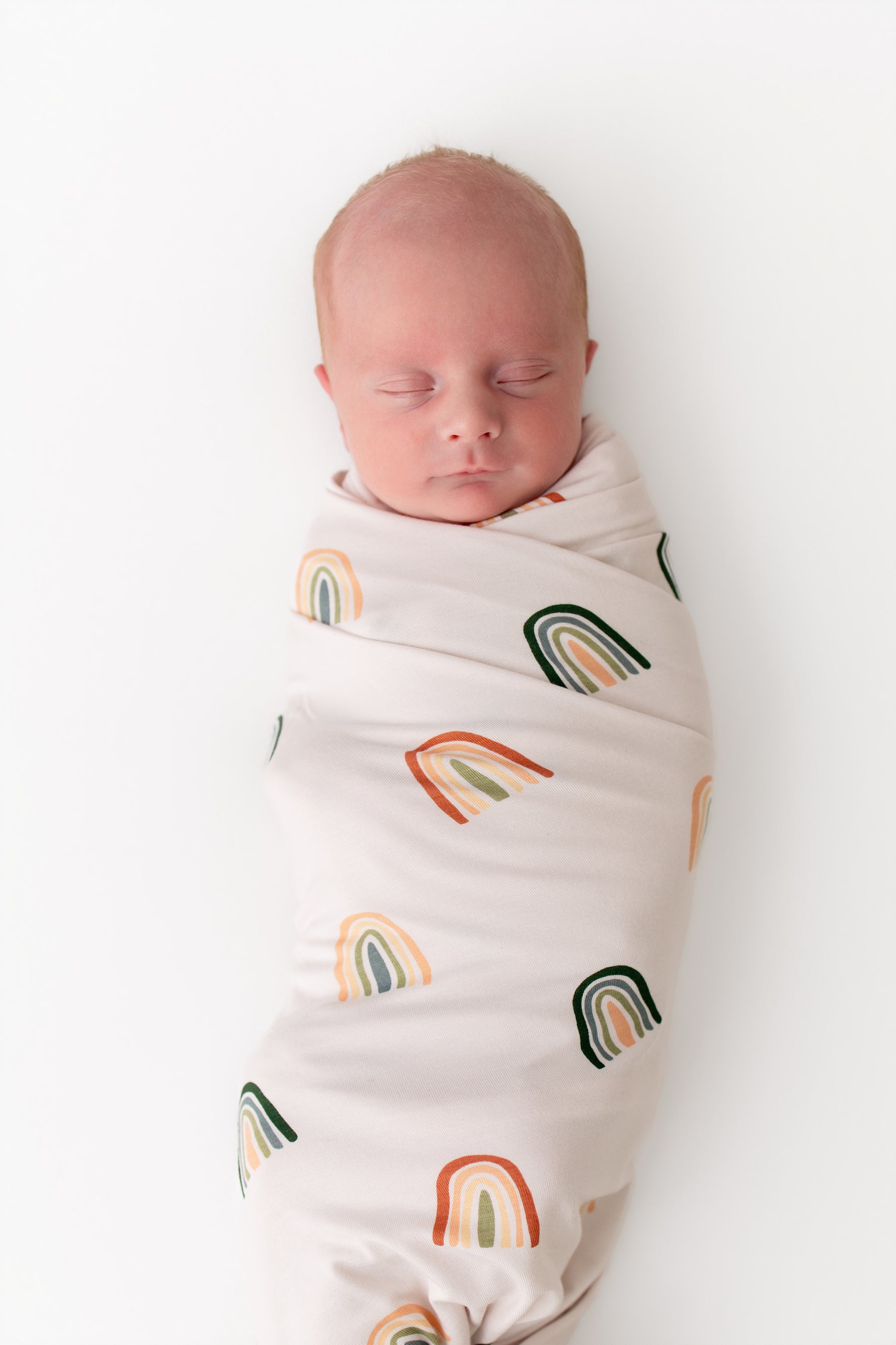 Baby sleeping in Swaddle Blanket in Retro Rainbow print on white background