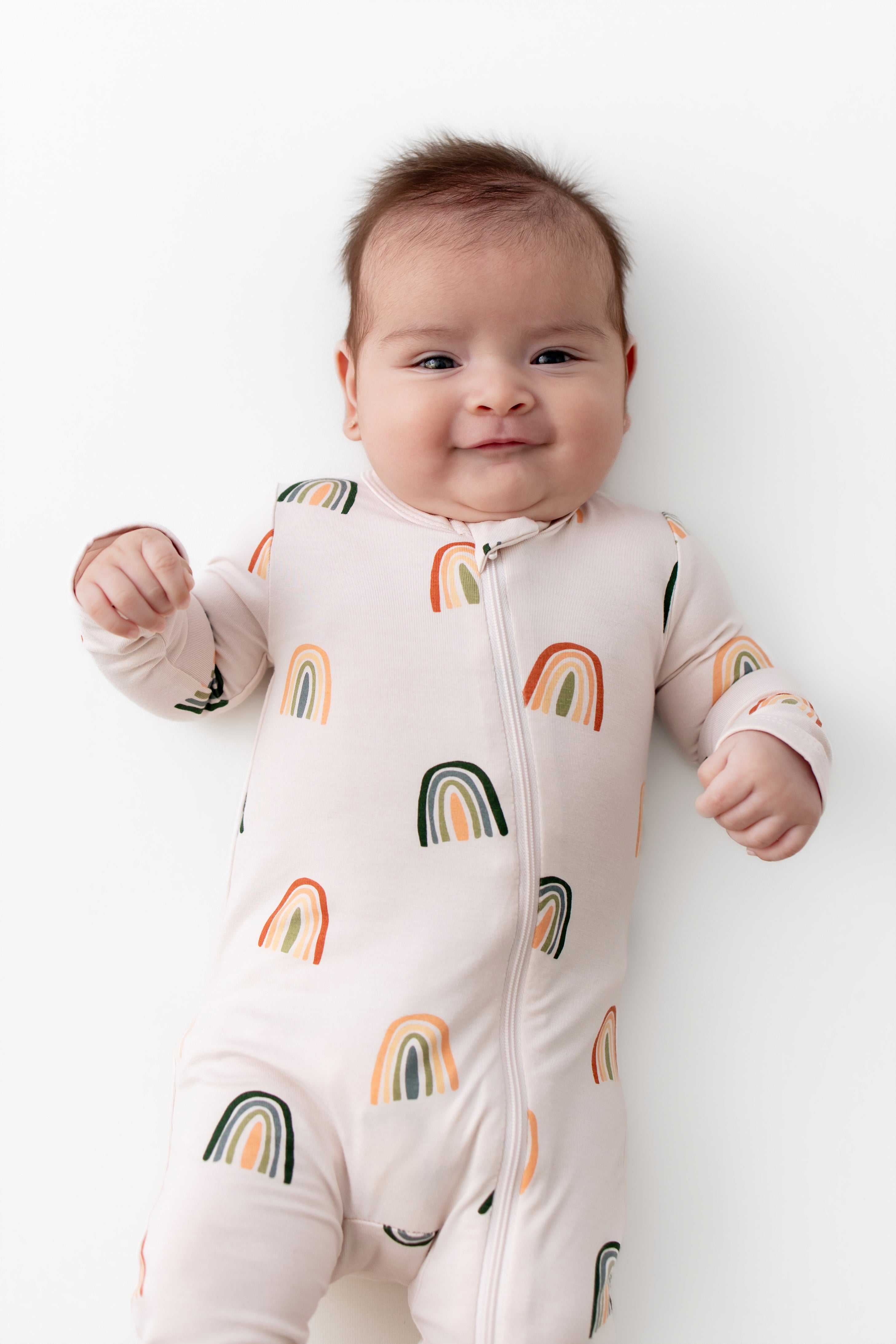 Baby in Zippered Romper with Retro Rainbow print on a white background