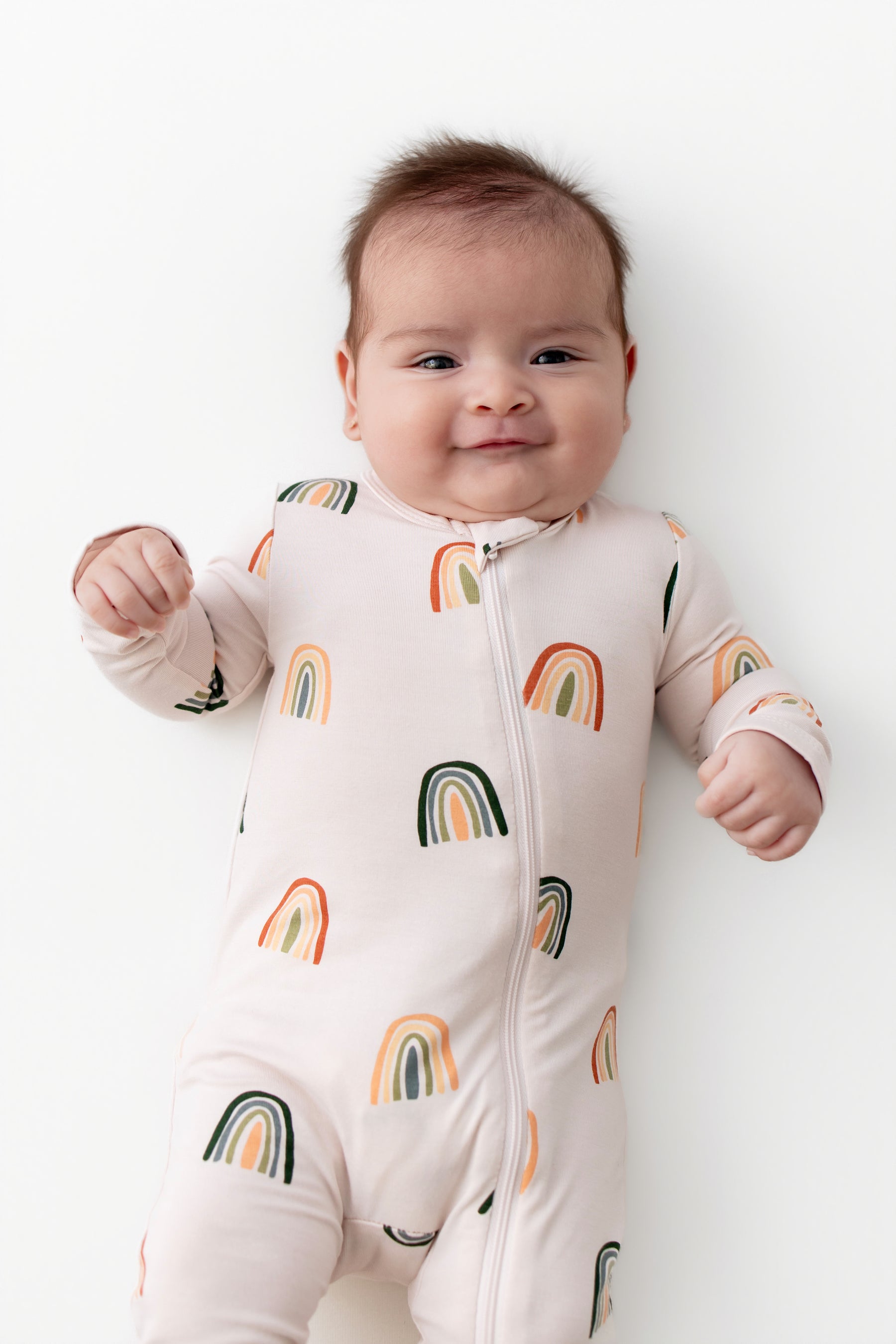 Baby in Zippered Romper with Retro Rainbow print on a white background
