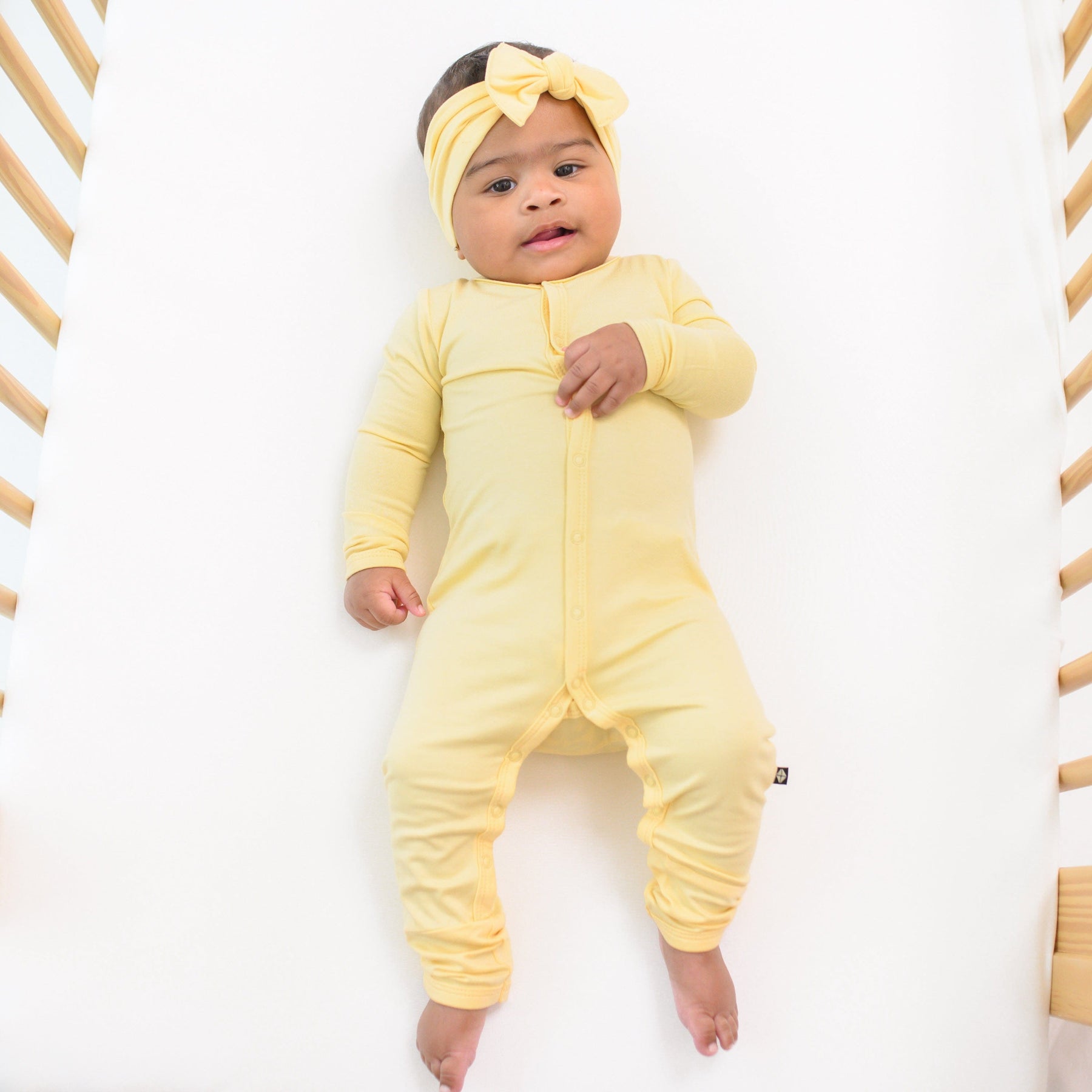 baby in snap romper and bow in the color lilikoi