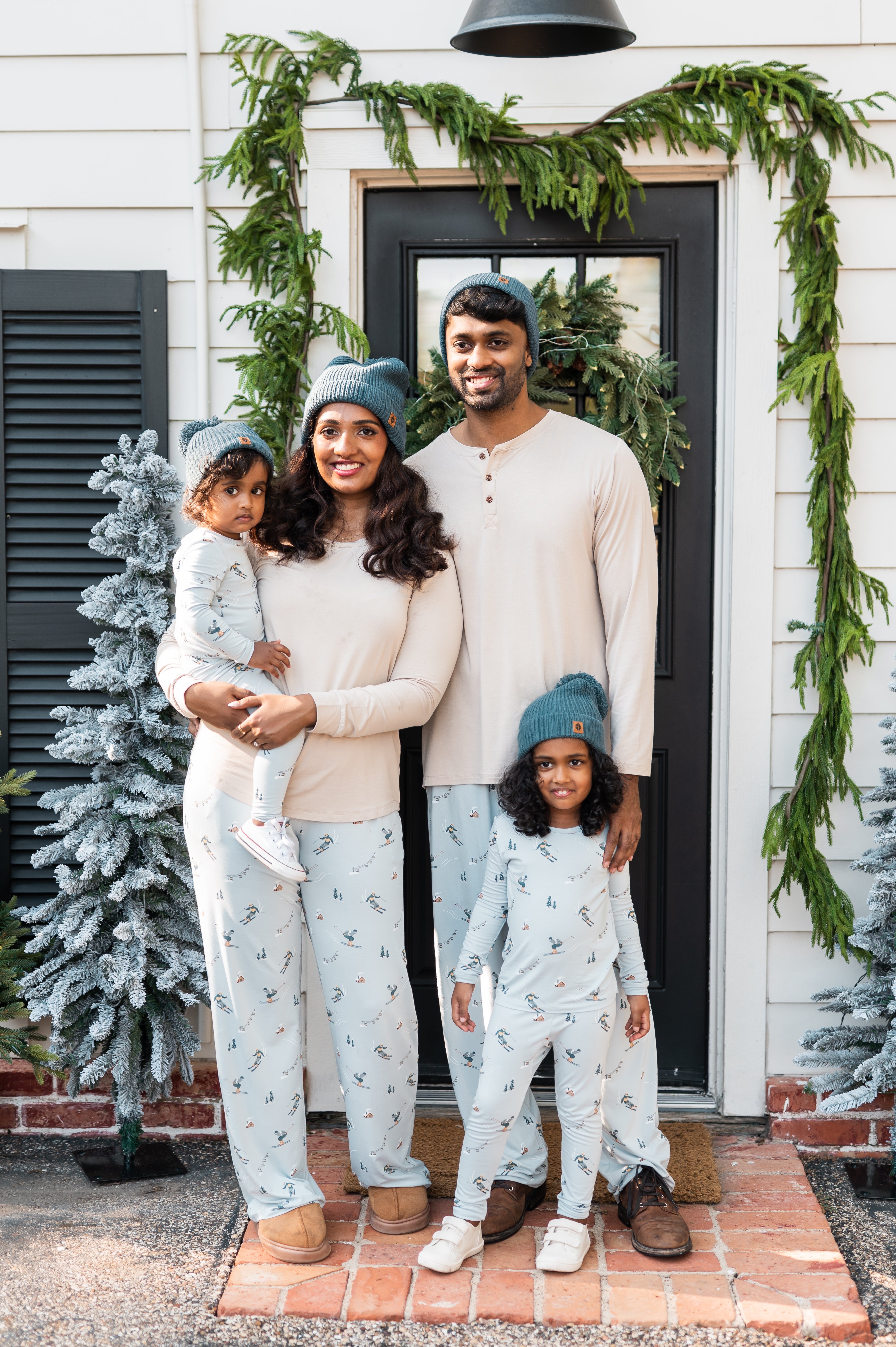 Family of four standing at a front door stoop, all matching in various Ski items
