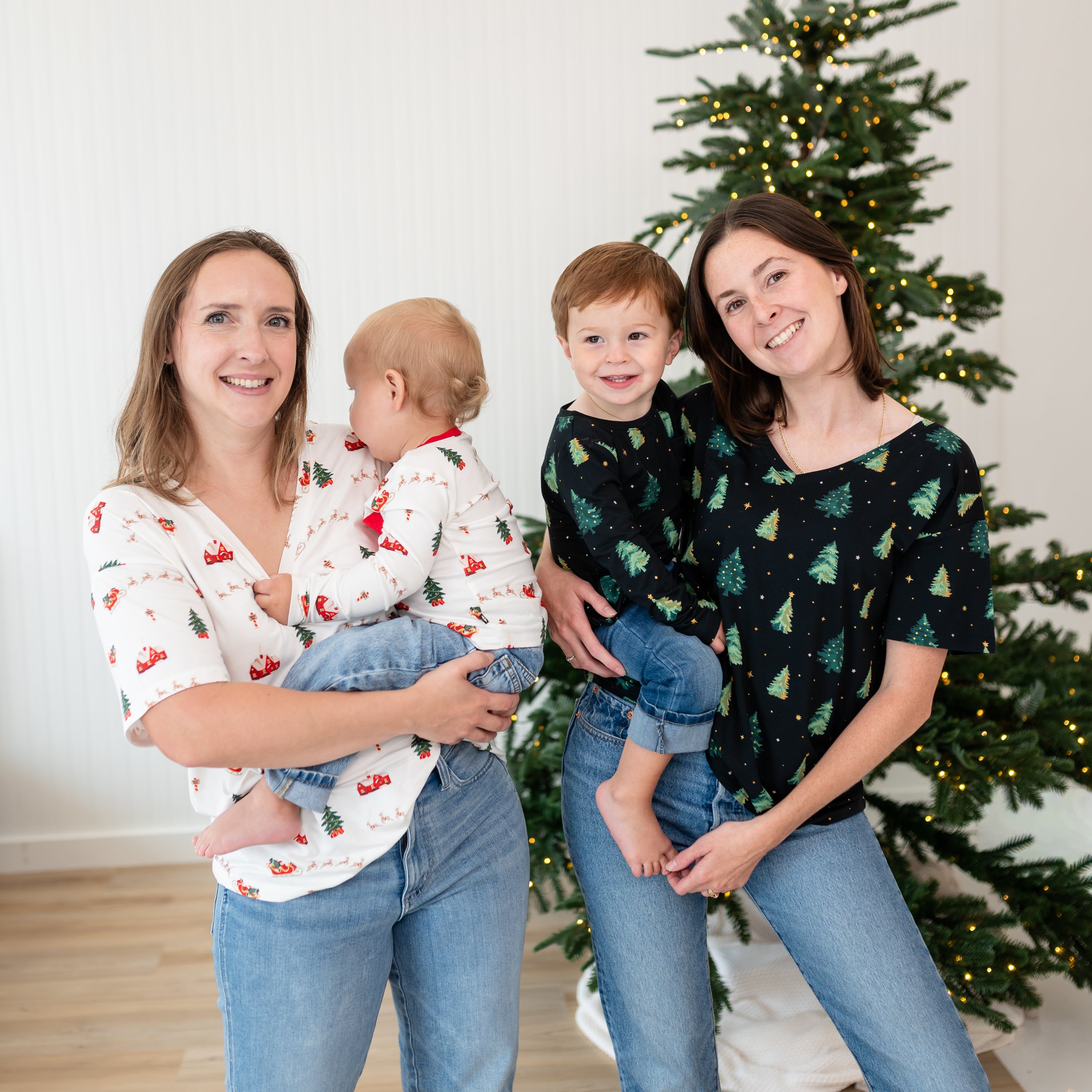 Group shot of two mothers with their two children matching in Twinkle Tree and Santa Sleigh Tee's